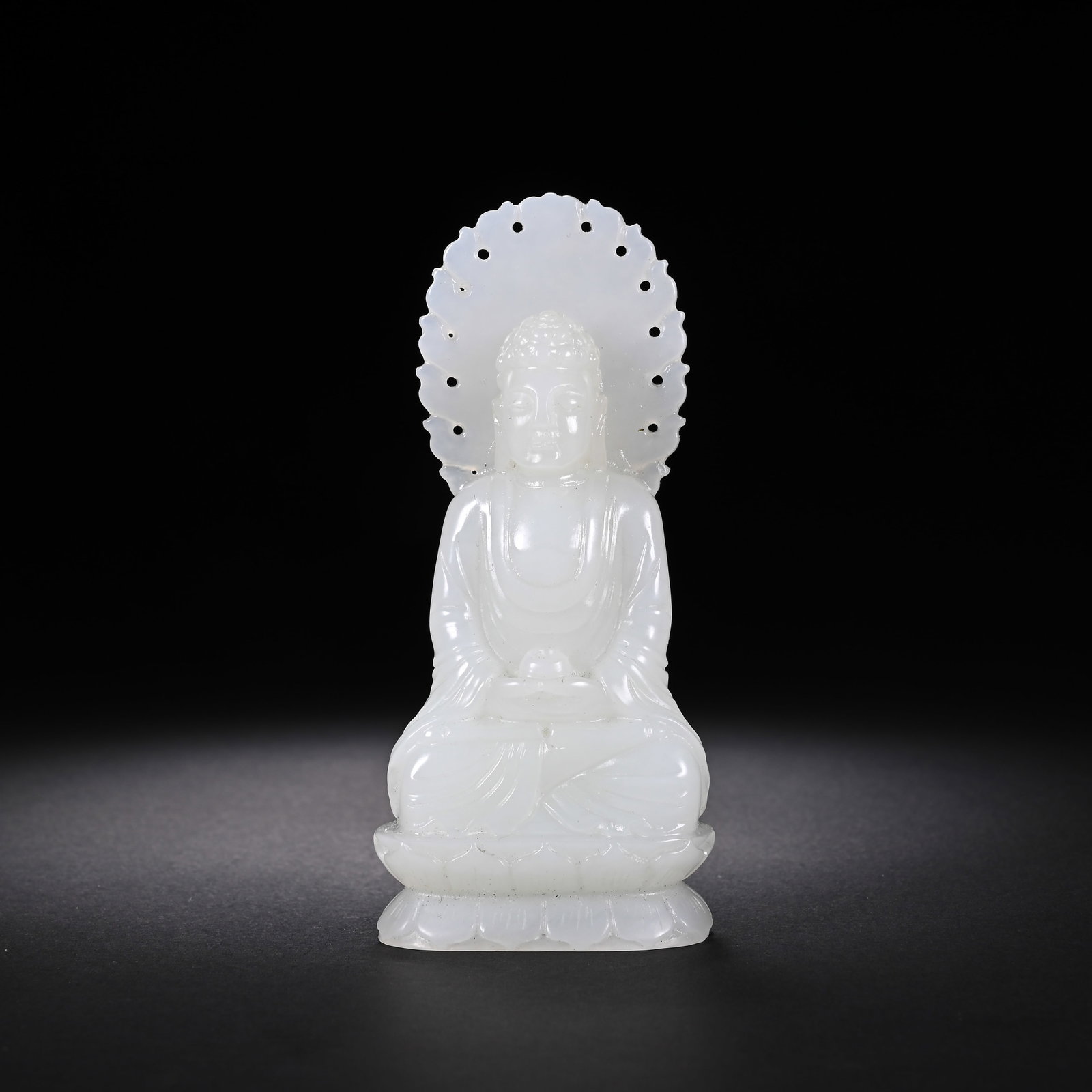 A CHINESE WHITE NEPHRITE JADE SEATED BUDDHA FIGURE: A CHINESE WHITE NEPHRITE JADE SEATED BUDDHA FIGURE Carved from fine milky white Hetian nephrite jade with a smooth lustrous polish, this Buddha statue sits in full lotus position atop a layered lotus 