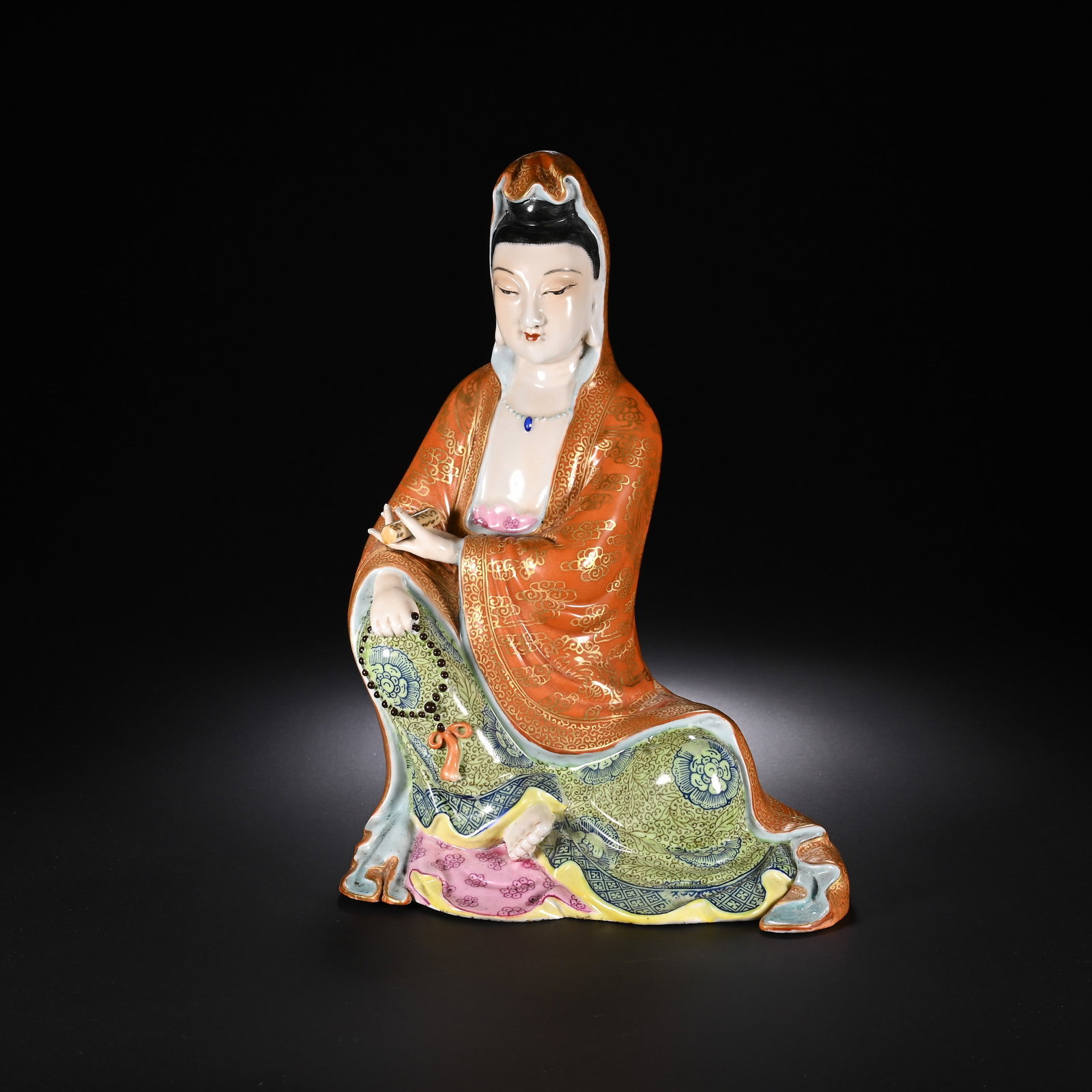 A CHINESE FAMILLE ROSE PORCELAIN GUANYIN FIGURE: A CHINESE FAMILLE ROSE PORCELAIN GUANYIN FIGURE This finely modelled porcelain Guanyin is depicted in a relaxed seated pose with serene downcast facial features and soft pale glaze on the face. She we