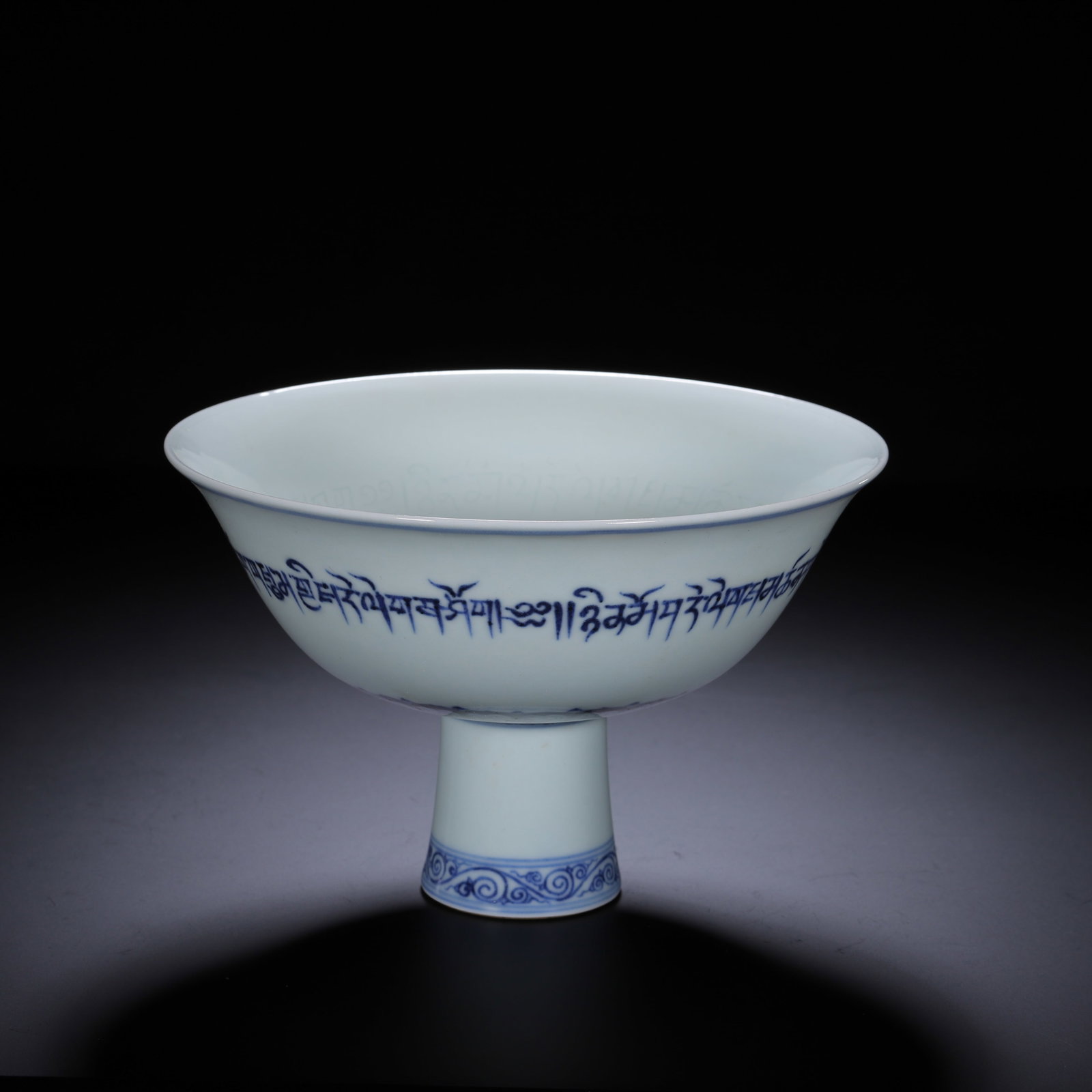 A CHINESE BLUE AND WHITE SCRIPT STEM BOWL: A CHINESE BLUE AND WHITE SCRIPT STEM BOWL This elegant stemmed bowl features a wide flared bowl supported by a stout cylindrical stem, covered in smooth pale white glaze. A continuous band of cobalt-b