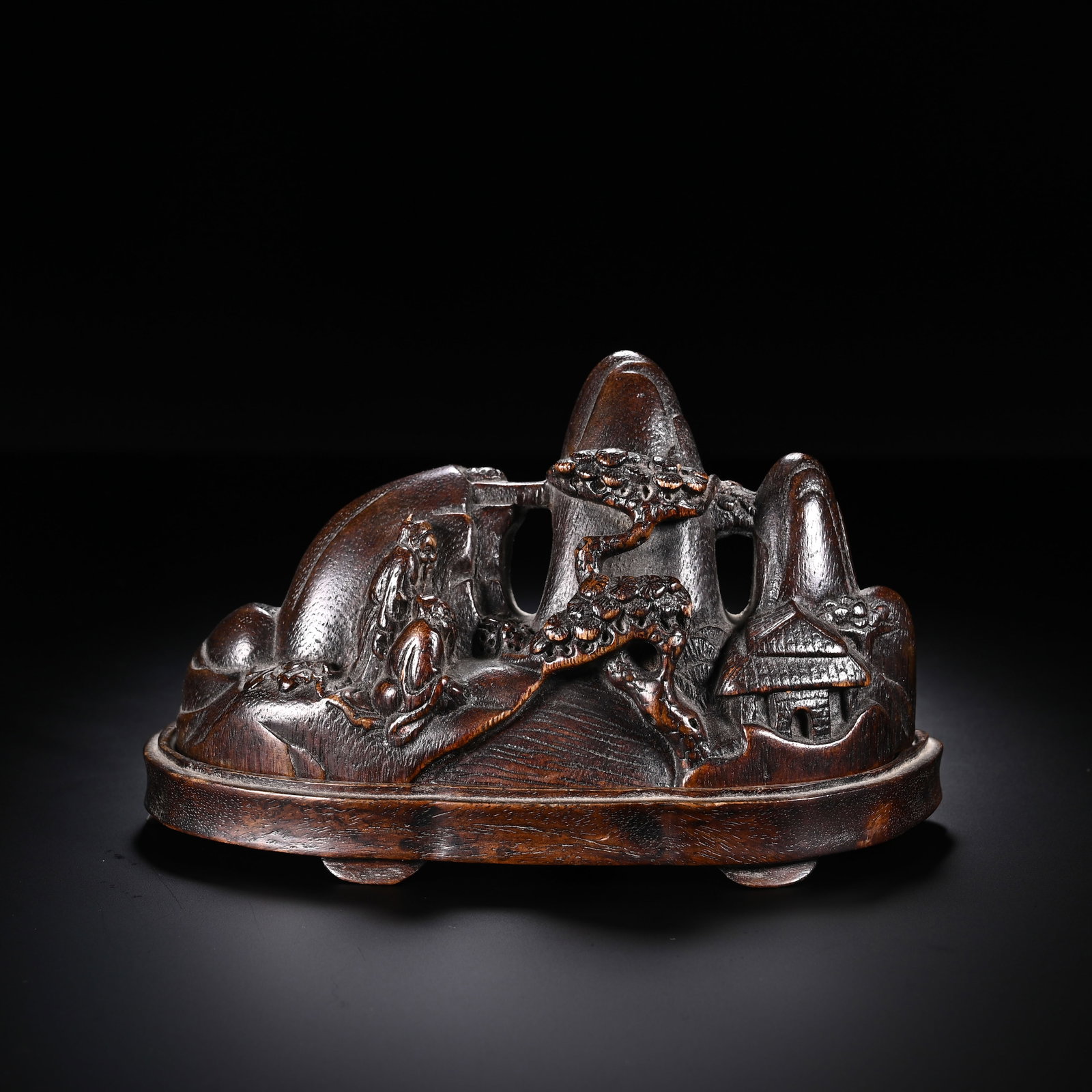 A CHINESE AGARWOOD MOUNTAIN BRUSH REST: A CHINESE AGARWOOD MOUNTAIN BRUSH REST This scholar's brush rest is fully carved from solid agarwood with a rich dark aged patina and subtle natural aromatic grain. Sculpted into a layered miniature m