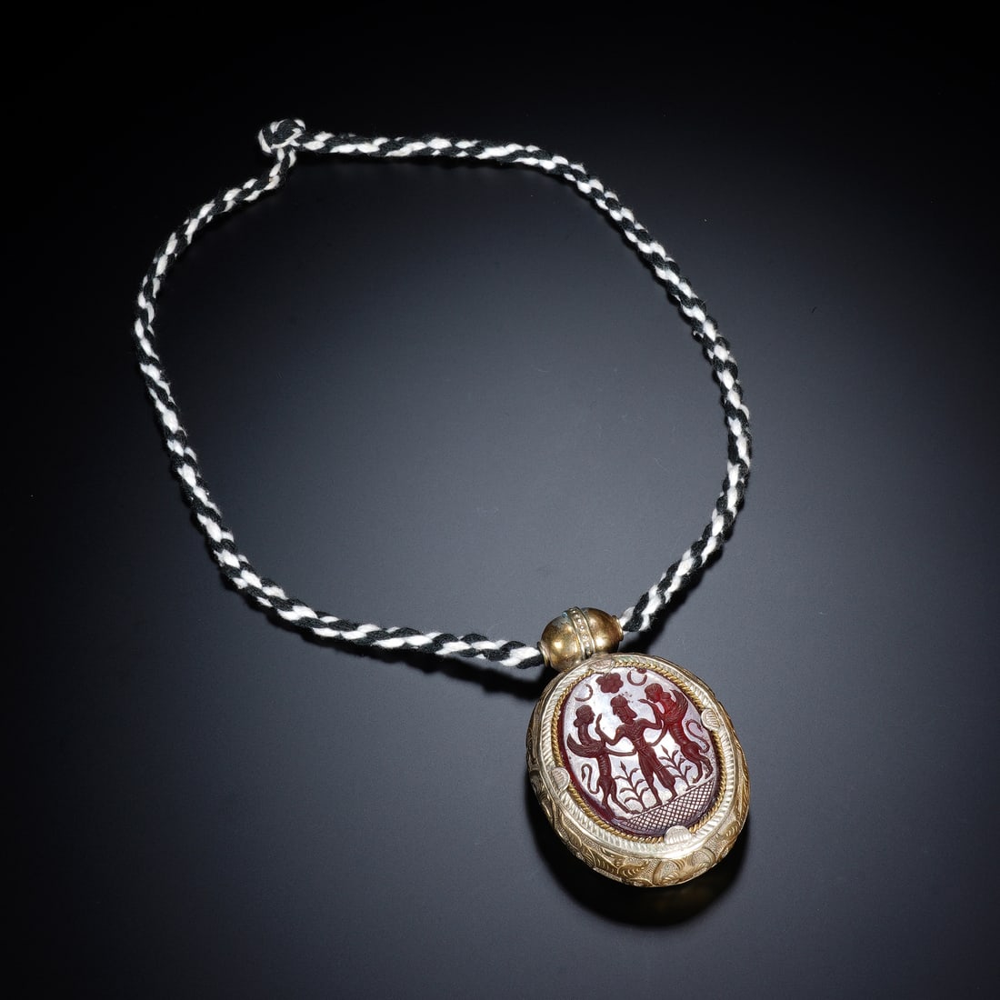 A CHINESE GILT AGATE INLAID GAU PENDANT: A CHINESE GILT AGATE INLAID GAU PENDANT This portable Tibetan Buddhist gau amulet case is crafted from bronze finished in rich lustrous gilding, with its oval front panel inset with carved banded agat