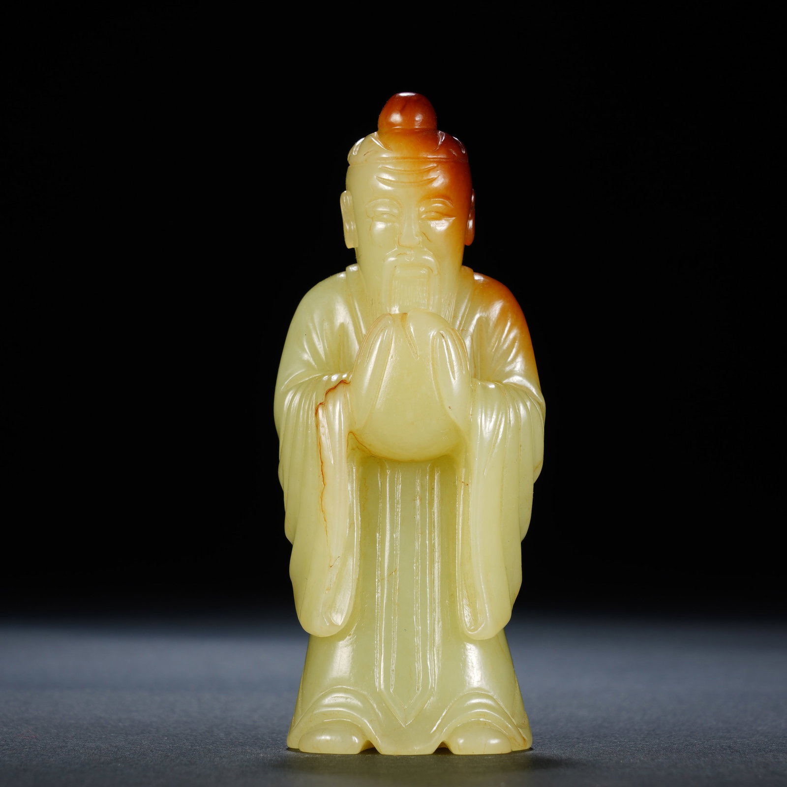 A CHINESE RUSSET SKIN YELLOW JADE STANDING GOD OF LONGEVITY: A CHINESE RUSSET SKIN YELLOW JADE STANDING GOD OF LONGEVITY This standing Shouxing carving measures 3.5cm ? 2.5cm ? 8cm and weighs 84 grams, crafted from warm pale yellow nephrite with natural russet 