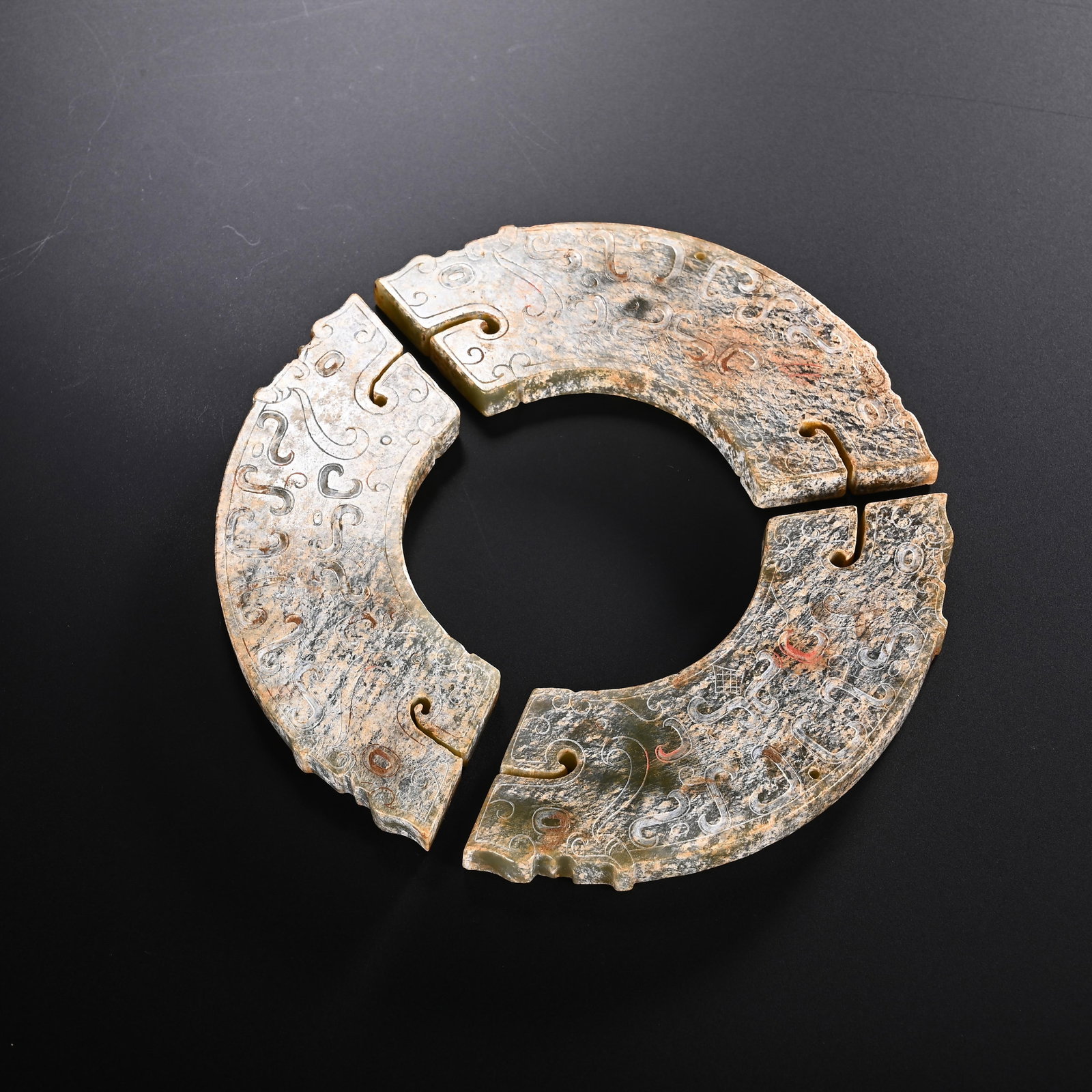 A CHINESE FOUR-PART ARCHAIC JADE BI DISC: A CHINESE FOUR-PART ARCHAIC JADE BI DISC This circular ritual bi is assembled from four interlocking jade segments fitted with notched tongue-and-groove joints around the ring. The jade bears extensiv