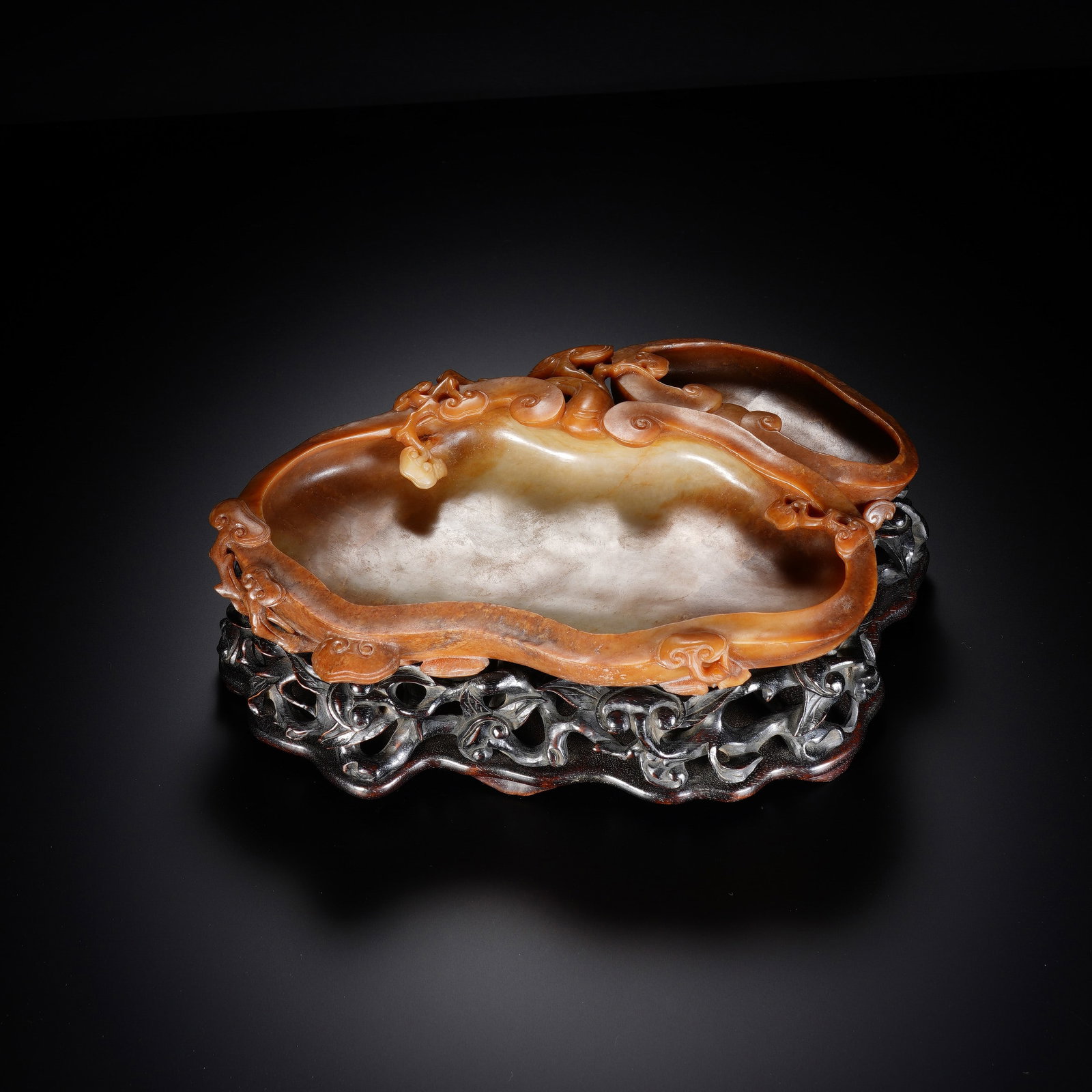 A CHINESE RUSSET-INFUSED JADE LINGZHI BAT BRUSH WASHER: A CHINESE RUSSET-INFUSED JADE LINGZHI BAT BRUSH WASHER This carved jade brush washer measures 21cm ? 14cm ? 3cm, standing 7cm tall overall with its hardwood stand, and weighs 551 grams. Crafted from n