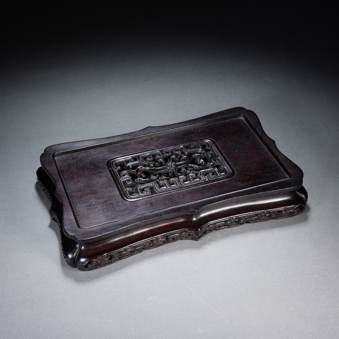 A CHINESE ZITAN OPENWORK CHILONG DISPLAY STAND: A CHINESE ZITAN OPENWORK CHILONG DISPLAY STAND Crafted from solid, richly grained polished zitan hardwood, this rectangular scholar's stand features soft undulating scalloped edges. Its central inset 