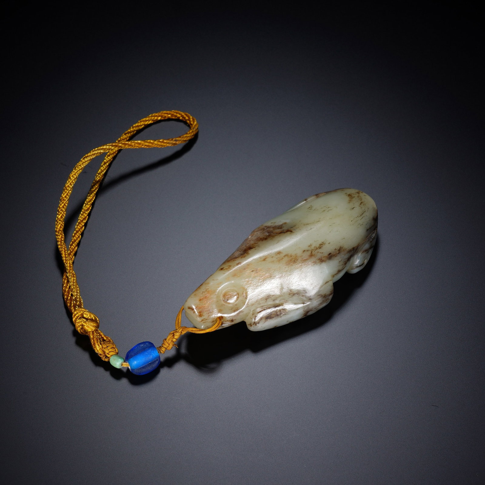 A CHINESE ARCHAIC JADE MYTHICAL BEAST PENDANT: A CHINESE ARCHAIC JADE MYTHICAL BEAST PENDANT This jade mythical beast carving measures 4.5cm ? 9.7cm ? 3cm and weighs 164 grams. Rendered in a streamlined recumbent form, the creature features a simp