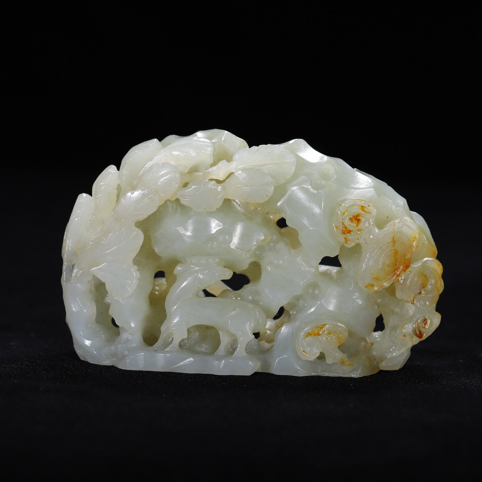 A CHINESE HETIAN JADE ORNAMENT: A CHINESE HETIAN JADE ORNAMENT This openwork carved ornament is crafted from pale celadon Hetian nephrite jade, retaining natural russet skin inclusions on its right side. Intricate hollowed carving d