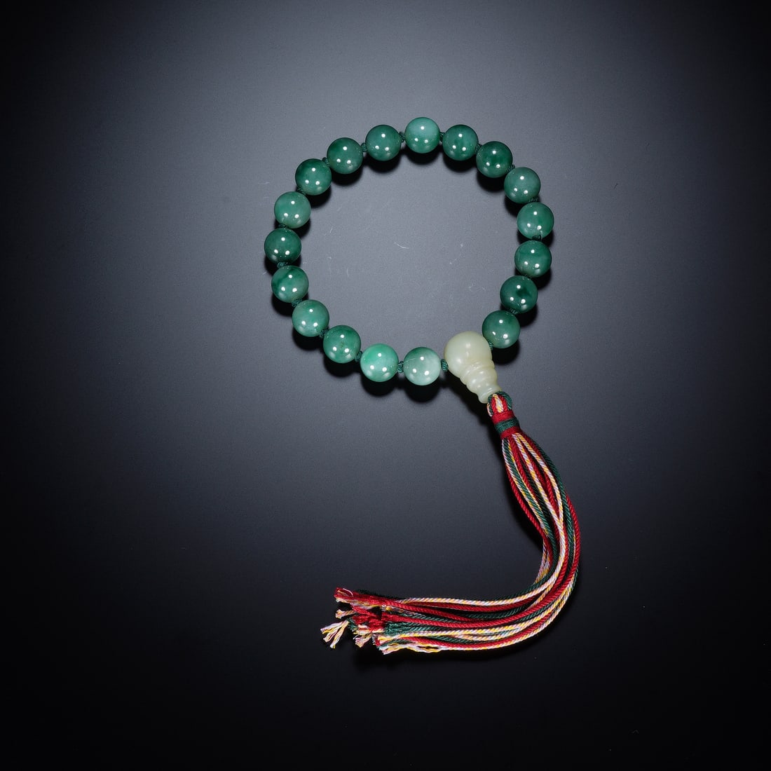A CHINESE JADEITE EIGHTEEN-BEAD PRAYER BRACELET: A CHINESE JADEITE EIGHTEEN-BEAD PRAYER BRACELET This traditional eighteen-bead handheld rosary is strung with uniform spherical jadeite beads, each 1.3 cm in diameter, exhibiting soft translucent