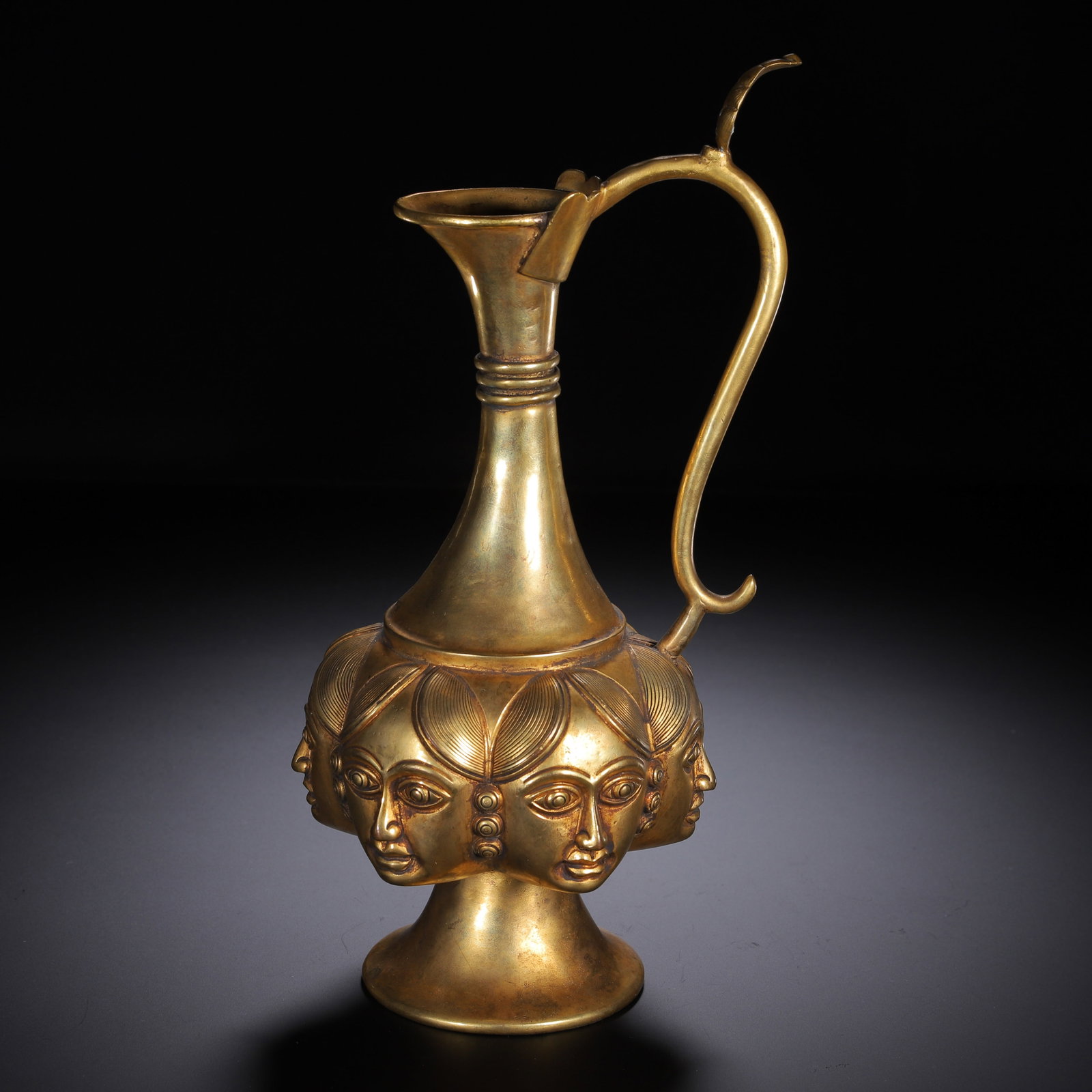 A CHINESE GILT BRONZE MULTI-FACED WINE EWER: A CHINESE GILT BRONZE MULTI-FACED WINE EWER Crafted from polished gilt bronze, this elegant ewer features a flared trumpet mouth, slender tapering neck wrapped with triple ring bands, and a curved scr