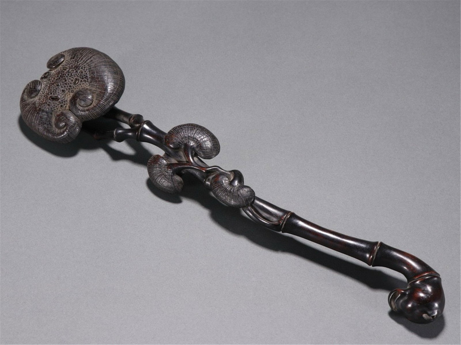 A CHINESE ZITAN WOOD RUYI SCEPTRE CARVED WITH LINGZHI FUNGUS: A CHINESE ZITAN WOOD RUYI SCEPTRE CARVED WITH LINGZHI FUNGUS This fine hardwood ornament measures 39cm long, 9.2cm wide and weighs 209 grams, entirely carved from dense polished zitan wood with a