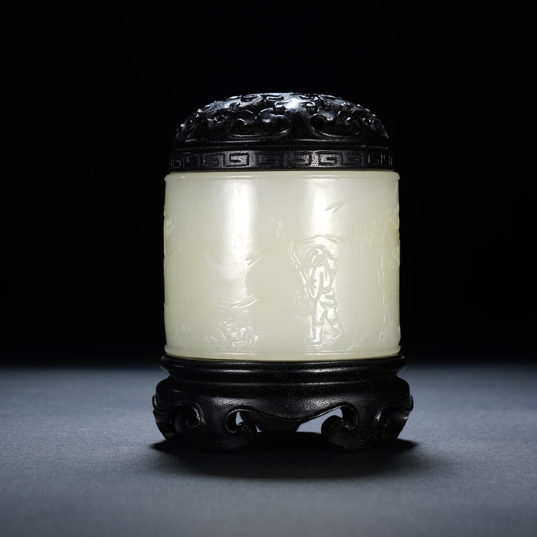 A CHINESE WHITE JADE CENSER WITH ZITAN LID & STAND: A CHINESE WHITE JADE CENSER WITH ZITAN LID & STAND The cylindrical incense burner is carved from smooth pale white nephrite jade, its exterior finely relief-decorated with classical scenes of scholars