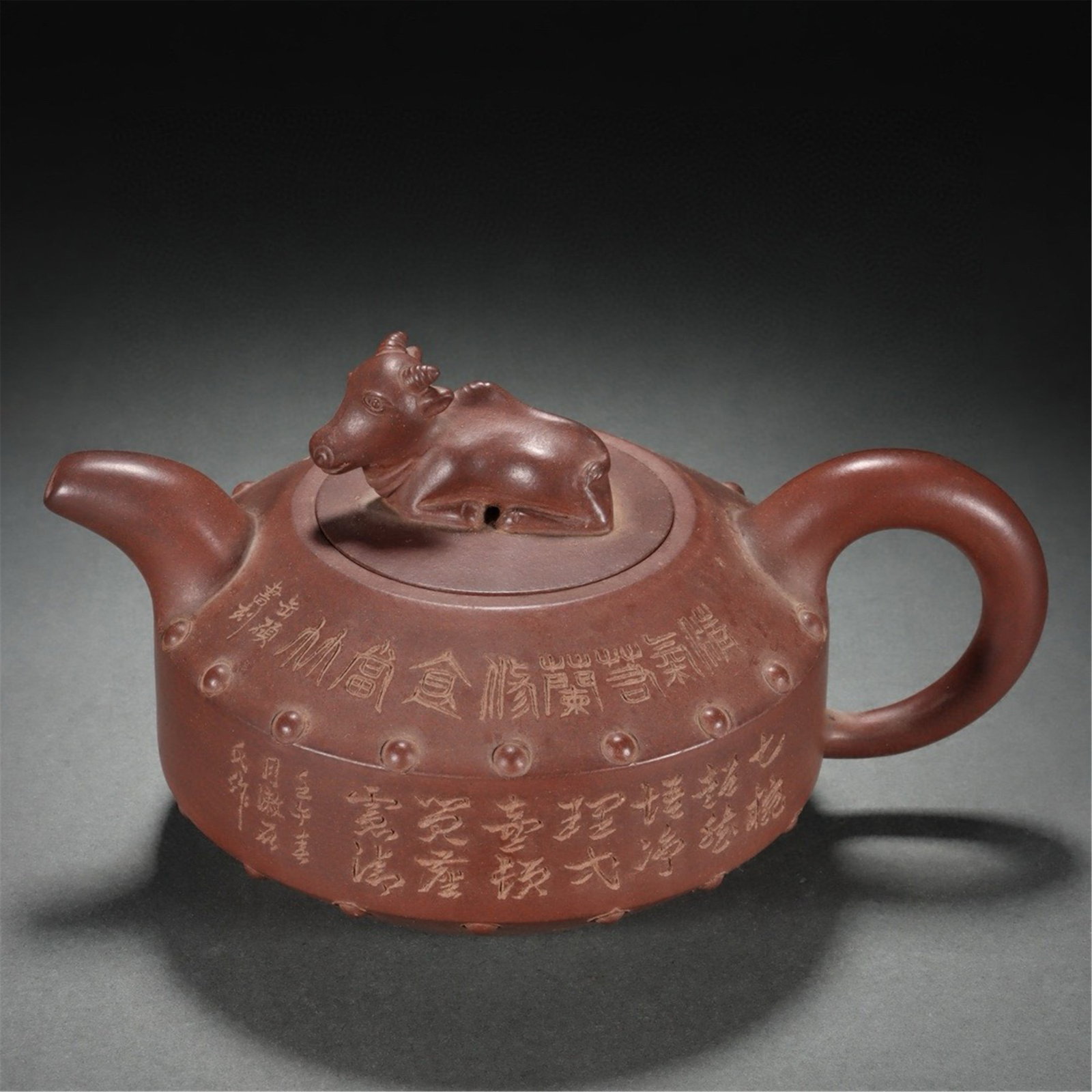 A CHINESE ZISHA TEAPOT WITH RECUMBENT BUFFALO FINIAL: A CHINESE ZISHA TEAPOT WITH RECUMBENT BUFFALO FINIAL Crafted from fine purplish-brown zisha clay, this hand-thrown teapot features a drum-shaped body lined with raised stud bosses encircling the midse