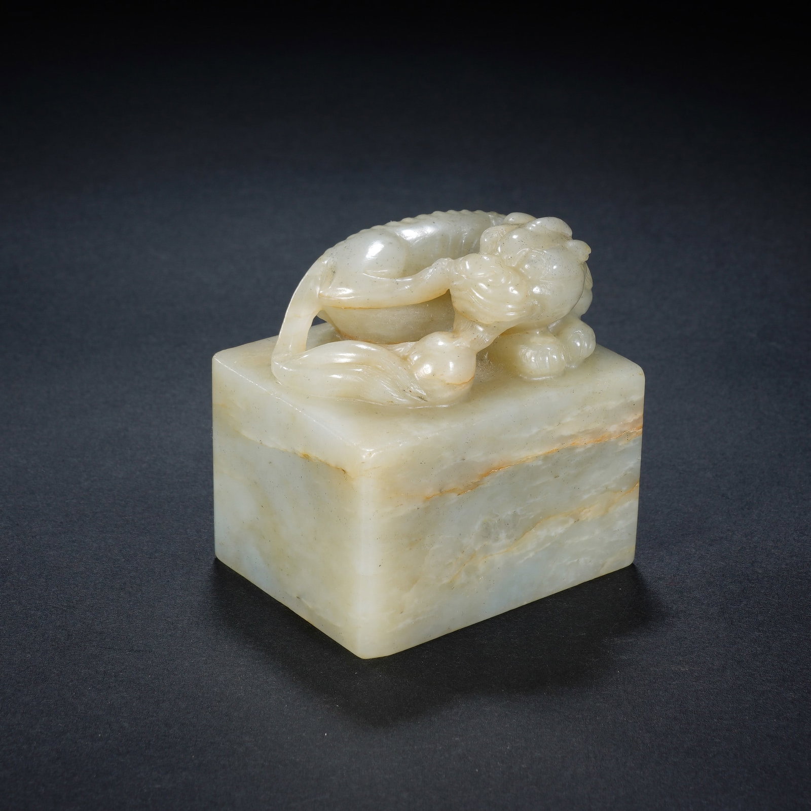 A CHINESE WHITE JADE MYTHICAL BEAST SEAL: A CHINESE WHITE JADE MYTHICAL BEAST SEAL This square white nephrite seal measures 5.7 cm wide, 4.6 cm deep and 6 cm tall, weighing 311 grams. The rectangular block features soft natural russet veining