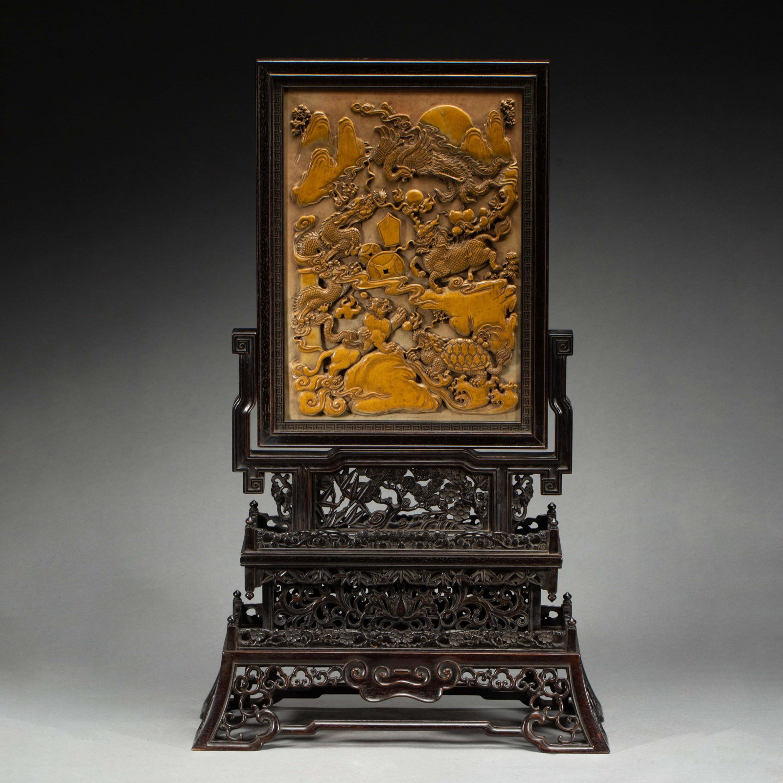 A CHINESE ZITAN FRAMED SHOUSHAN STONE TABLE SCREEN: A CHINESE ZITAN FRAMED SHOUSHAN STONE TABLE SCREEN An elaborate table screen housed within a solid carved zitan wood stand with deep dark lustre. The rectangular plaque is sculpted from warm golden Sh