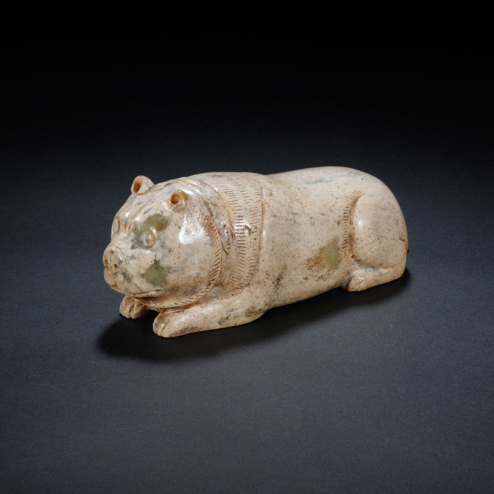 A CHINESE ARCHAIC RECUMBENT JADE BEAR: A CHINESE ARCHAIC RECUMBENT JADE BEAR This jade bear carving measures 14cm ? 5cm ? 5cm and weighs 549 grams, modelled in a serene prone posture with its front paws tucked forward. Fine incised linear 