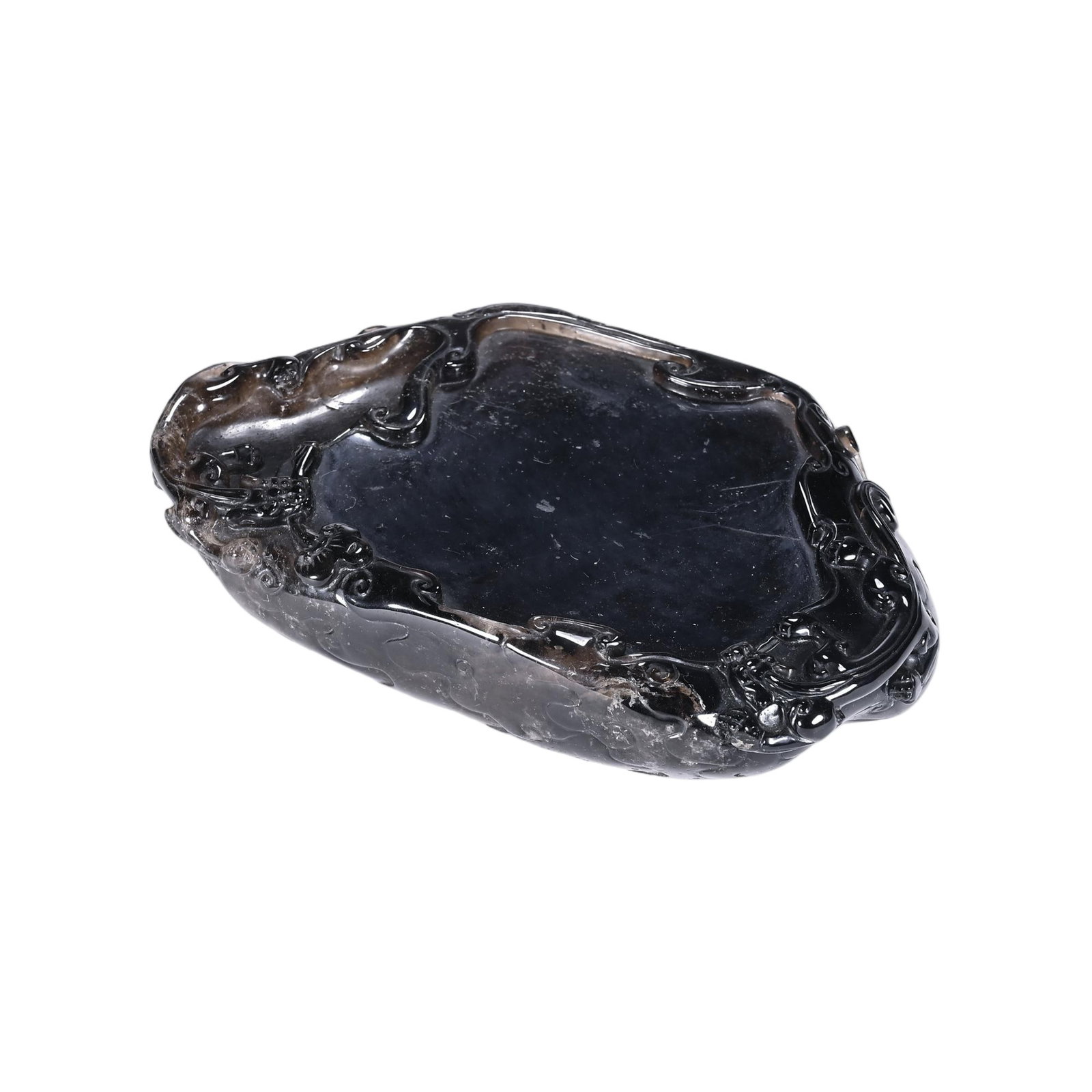 A CHINESE SMOKY ROCK CRYSTAL INK STONE: A CHINESE SMOKY ROCK CRYSTAL INK STONE Carved from dark smoky rock crystal, this irregular lobed ink slab is crafted for traditional Chinese calligraphy. Its central smooth grinding pool is surrounded