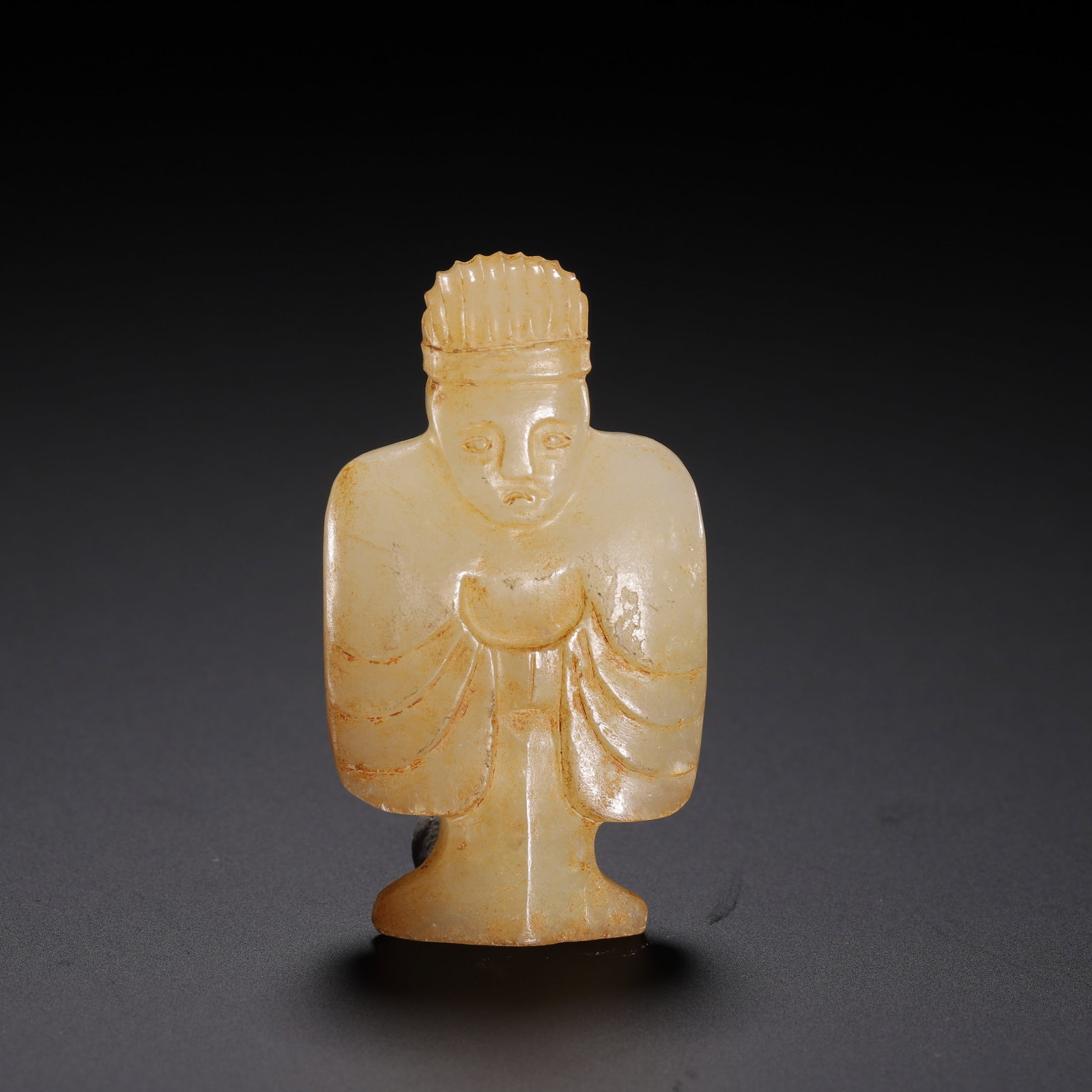 A CHINESE HETIAN JADE HUMAN FIGURE: A CHINESE HETIAN JADE HUMAN FIGURE This miniature standing figurine is carved from pale creamy Hetian nephrite jade, streaked with subtle russet aged patina across the polished surface. The figure wea