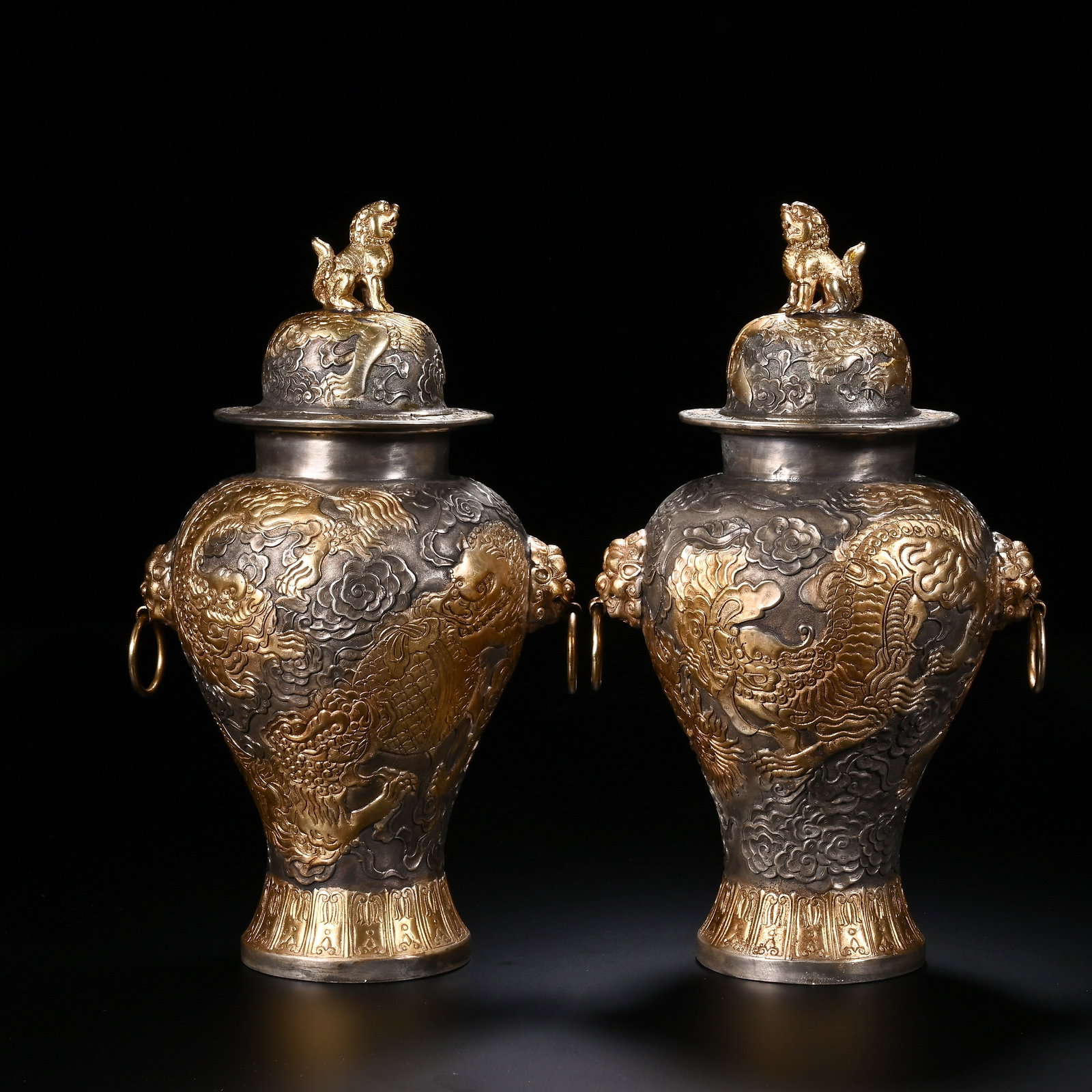 A PAIR OF CHINESE PARTIALLY GILT COPPER DRAGON JARS: A PAIR OF CHINESE PARTIALLY GILT COPPER DRAGON JARS This matching pair of lidded storage jars is cast in copper with silvered ground and lavish selective gilded repouss? relief. Each domed lid is crow
