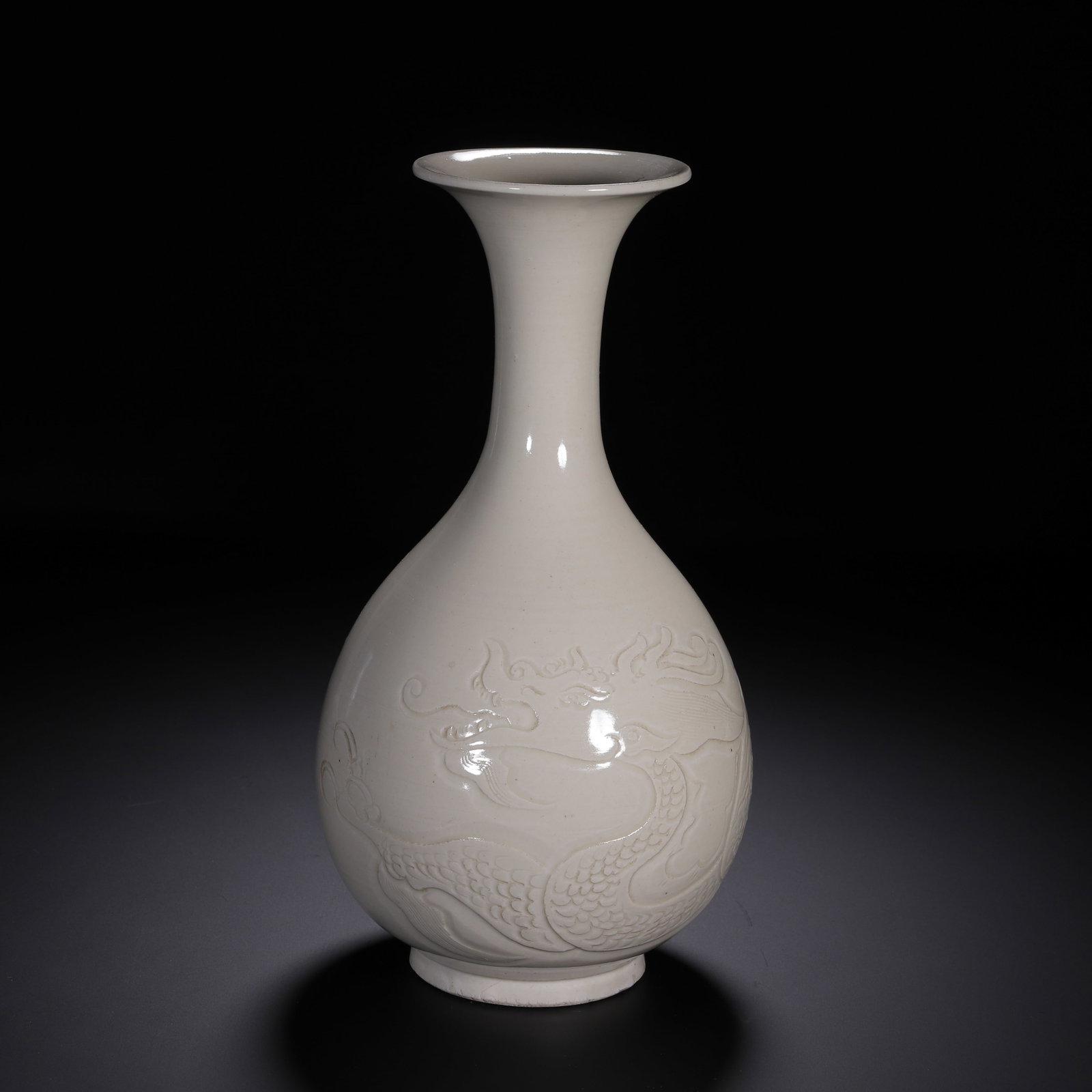 A WHITE GLAZE INCISED DRAGON PEAR-SHAPED VASE: A WHITE GLAZE INCISED DRAGON PEAR-SHAPED VASE This elegant pear-shaped porcelain vase is enveloped in smooth, lustrous creamy white glaze with a soft even finish. It features a flared wide rim, slende