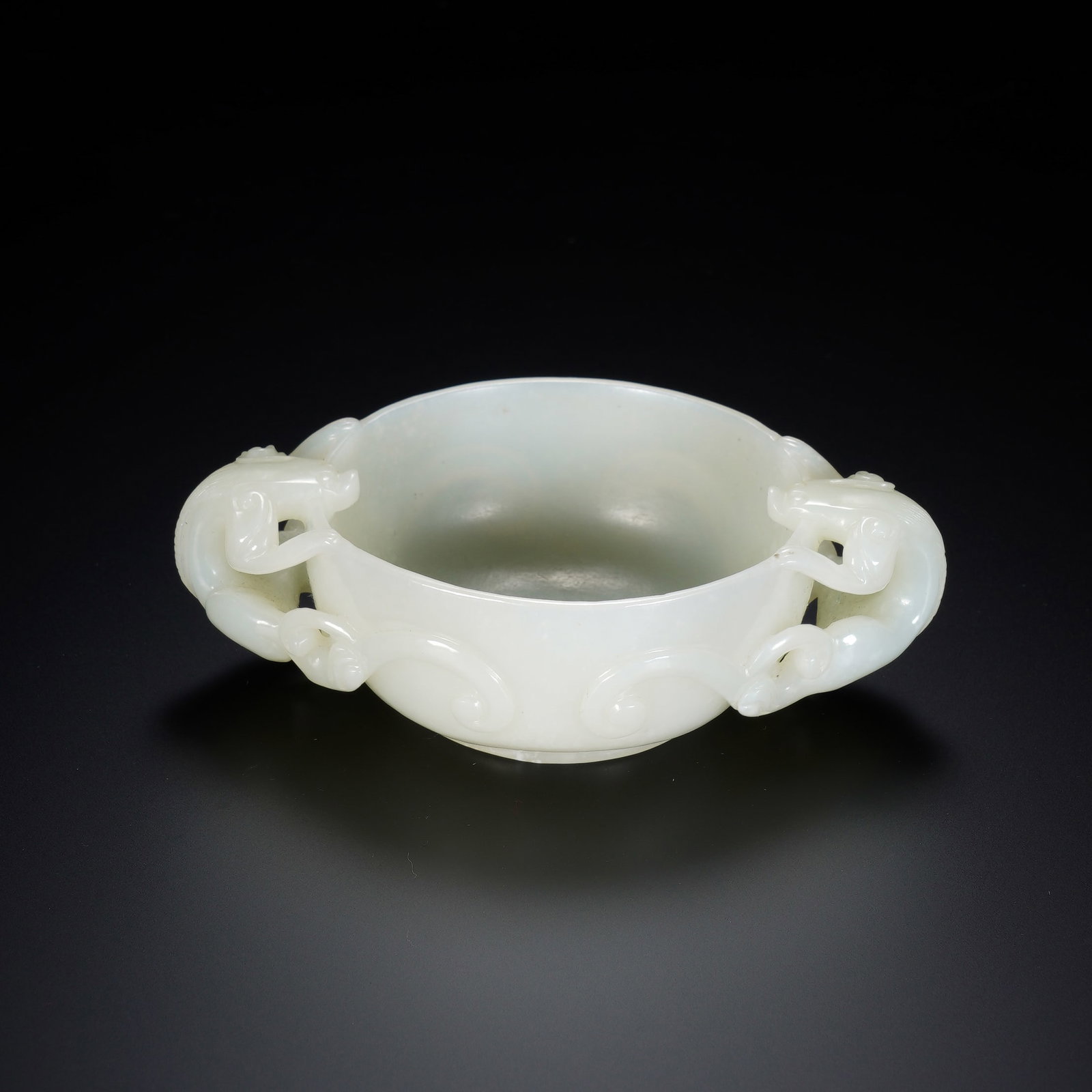 A CHINESE WHITE JADE CUP WITH TWIN CHILONG HANDLES: A CHINESE WHITE JADE CUP WITH TWIN CHILONG HANDLES This fine nephrite wine cup measures 10cm ? 6.8cm ? 3cm and weighs 103 grams, carved from lustrous creamy white jade with uniform smooth polish. The 
