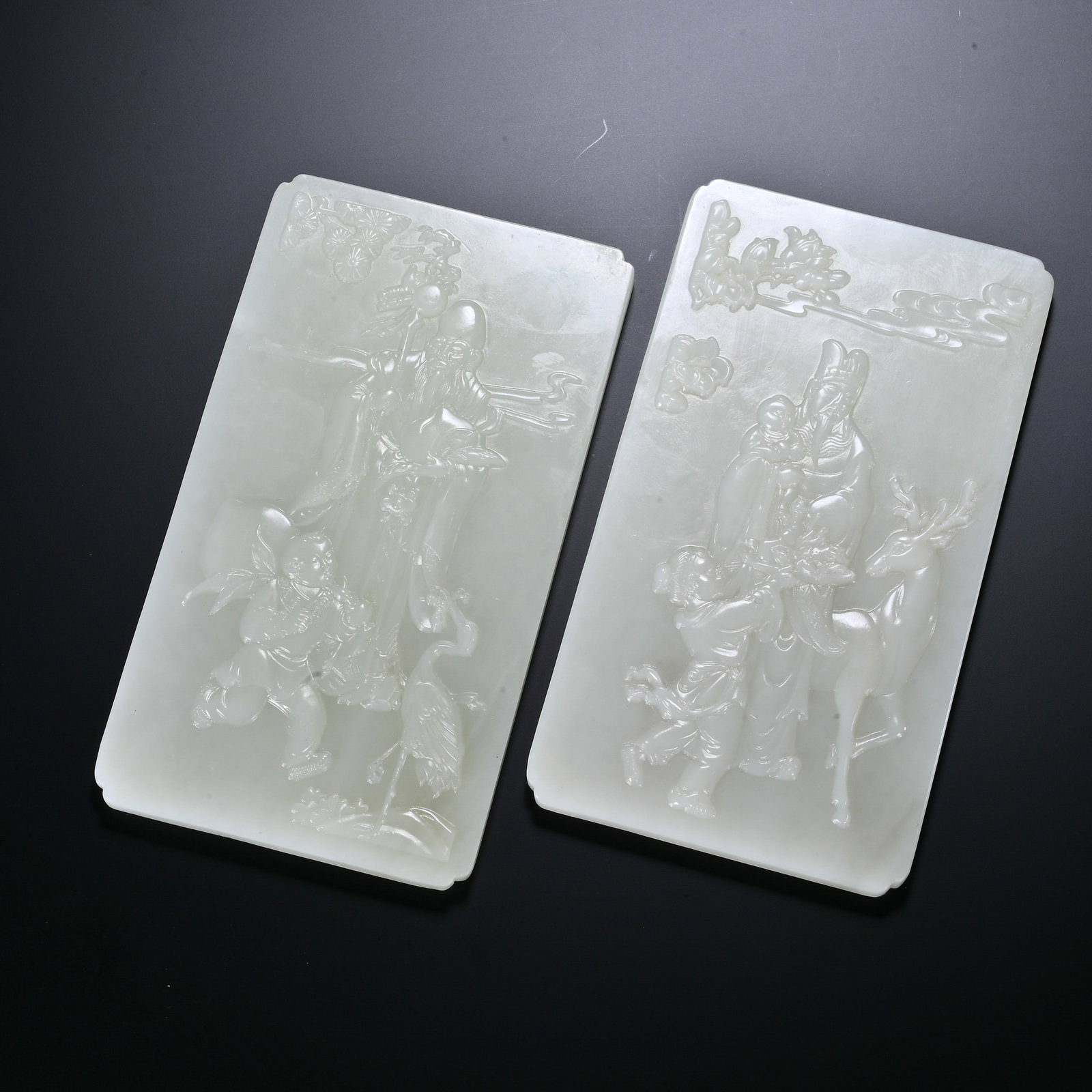 A PAIR OF CHINESE WHITE JADE FU LU SHOU PANELS: A PAIR OF CHINESE WHITE JADE FU LU SHOU PANELS This matched pair of rectangular plaques is carved from smooth milky white Hetian nephrite with a soft satiny polish, intended as table screen inserts. E