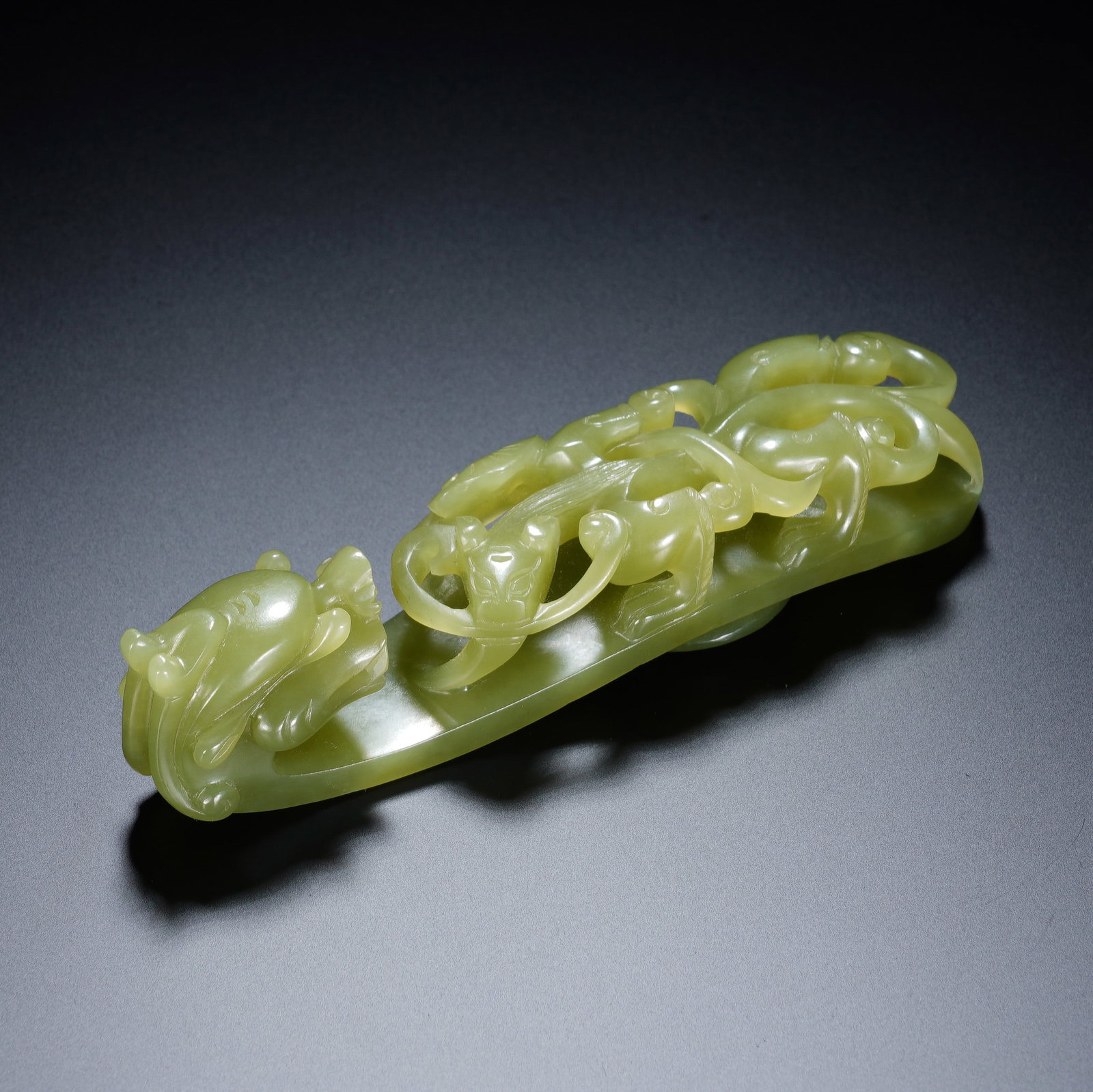 A CHINESE YELLOW JADE BELT HOOK: A CHINESE YELLOW JADE BELT HOOK This carved yellow jade belt hook measures 3 cm wide, 2.8 cm deep and 11.2 cm long, weighing 85 grams. The head is finely modelled as a stylised dragon head with smooth