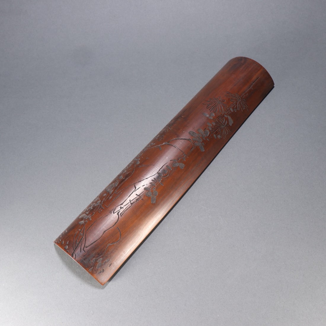 A CHINESE CARVED BAMBOO WRIST REST WITH FLORAL MOTIFS: A CHINESE CARVED BAMBOO WRIST REST WITH FLORAL MOTIFS This scholar's arm rest measures 30.1cm long, 6.6cm wide and weighs 86.4 grams, crafted from polished aged bamboo with a warm reddish-brown patina