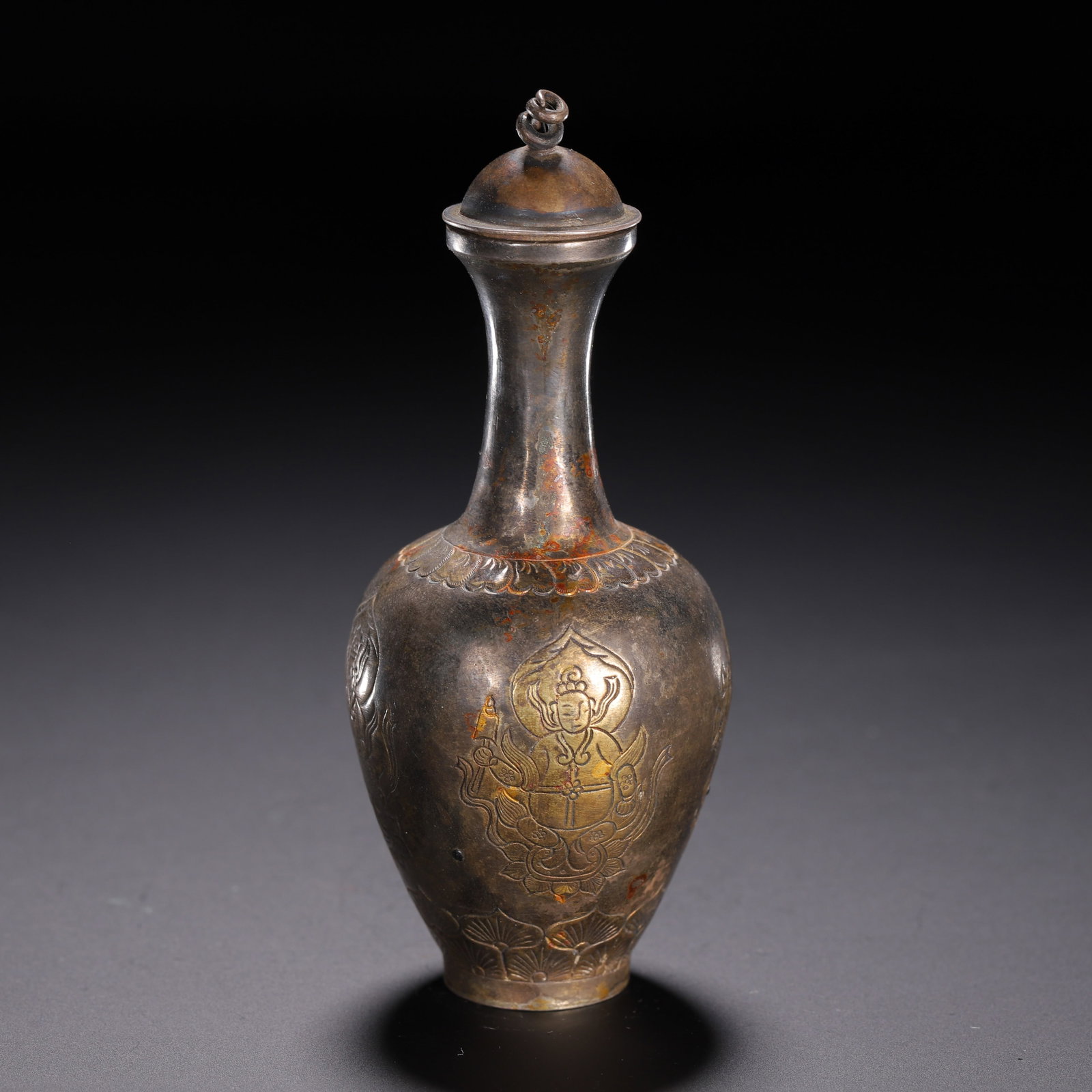 A CHINESE PARTIAL GILT SILVER BUDDHIST LIDDED VASE: A CHINESE PARTIAL GILT SILVER BUDDHIST LIDDED VASE This slender lidded silver vase boasts an elegant pear-shaped body rising to a tall narrow neck topped with a domed lid finished with a twisted ring 