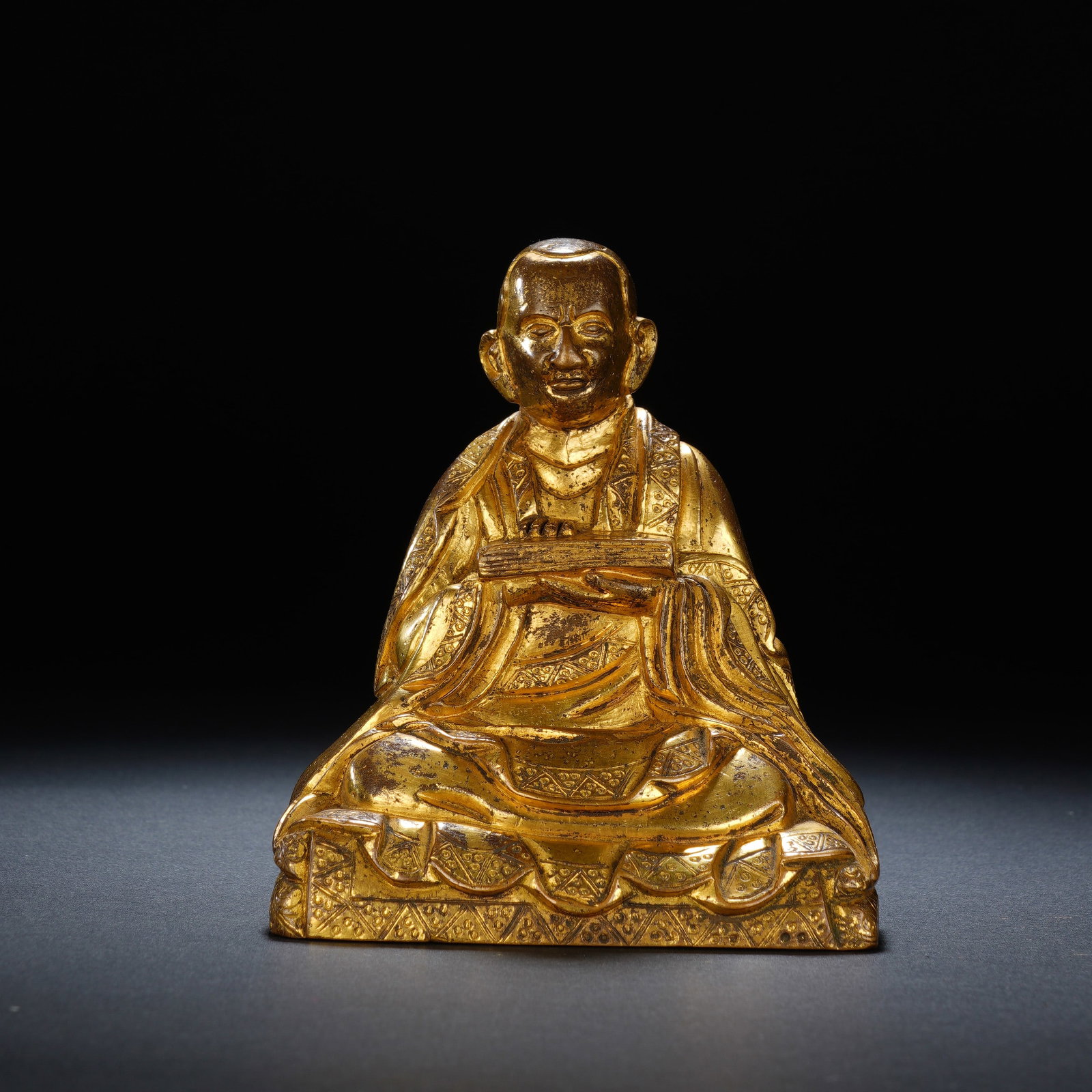 A CHINESE GILT BRONZE LAMA MASTER FIGURE: A CHINESE GILT BRONZE LAMA MASTER FIGURE This seated gilt bronze lama master statue measures 8.5 cm wide, 7 cm deep and 10 cm in height, weighing 641 grams. The guru sits in full lotus posture atop a 