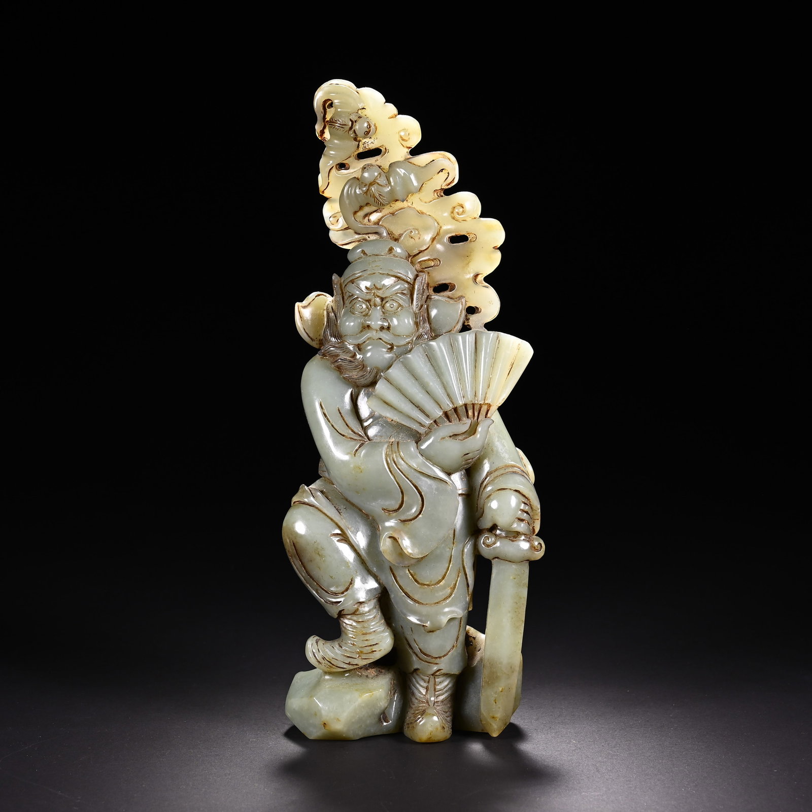 A CHINESE CELADON JADE FIGURE OF ZHONG KUI: A CHINESE CELADON JADE FIGURE OF ZHONG KUI This standing decorative carving is sculpted from celadon nephrite jade permeated with warm amber russet patina across the robes, cloud scrolls and facial de