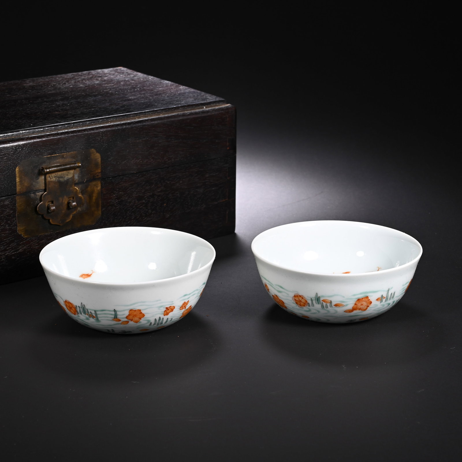 A PAIR OF CHINESE FAMILLE ROSE WATER LILY CUPS: A PAIR OF CHINESE FAMILLE ROSE WATER LILY CUPS This matched pair of shallow wine cups is potted from fine translucent white porcelain with wide flared rims and low rounded bodies. The exterior is deli