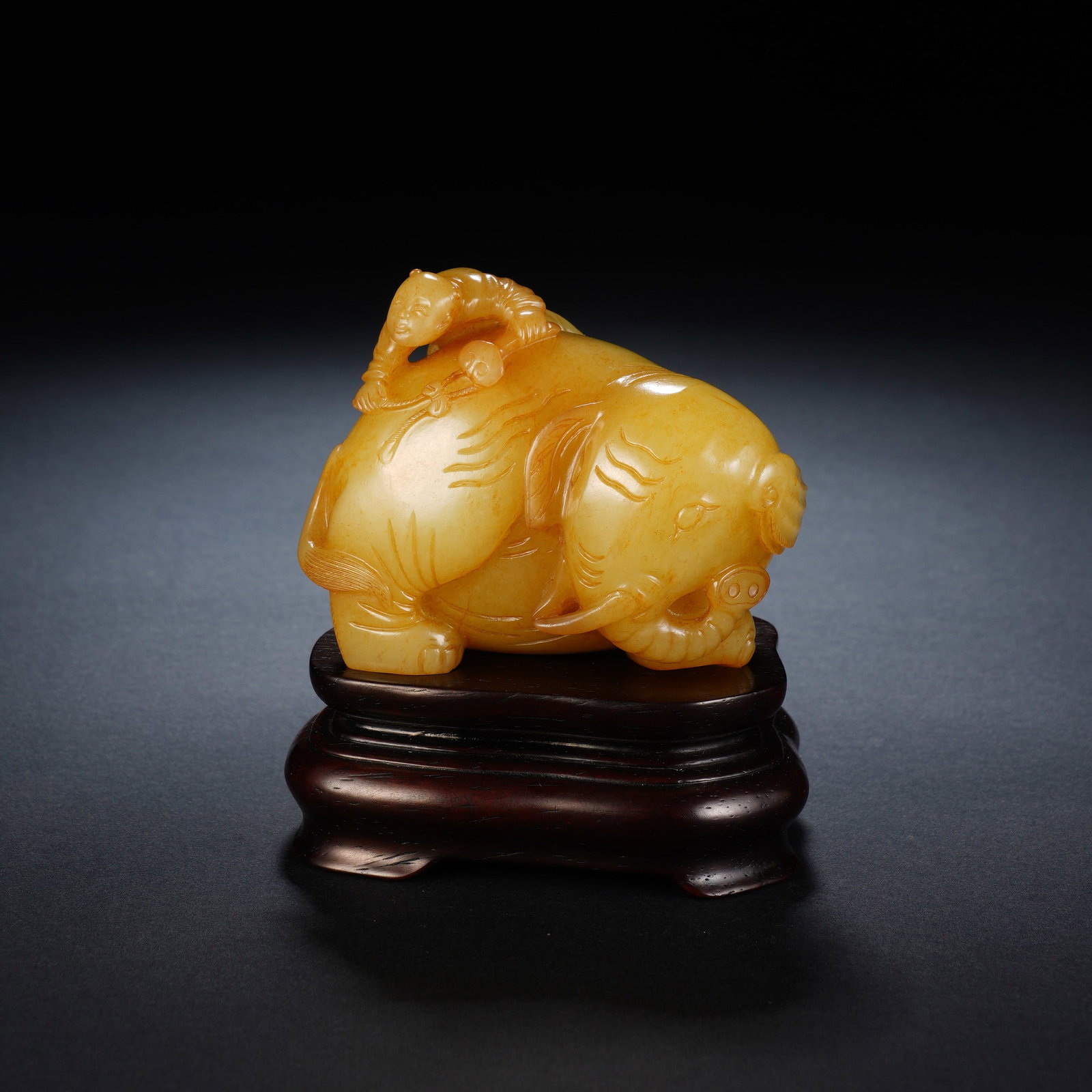 A CHINESE YELLOW JADE BOY AND ELEPHANT CARVING: A CHINESE YELLOW JADE BOY AND ELEPHANT CARVING This polished yellow jade carving measures 7cm ? 5cm ? 6cm, with an overall height of 9cm including its hardwood stand, weighing 271 grams. It depicts a 