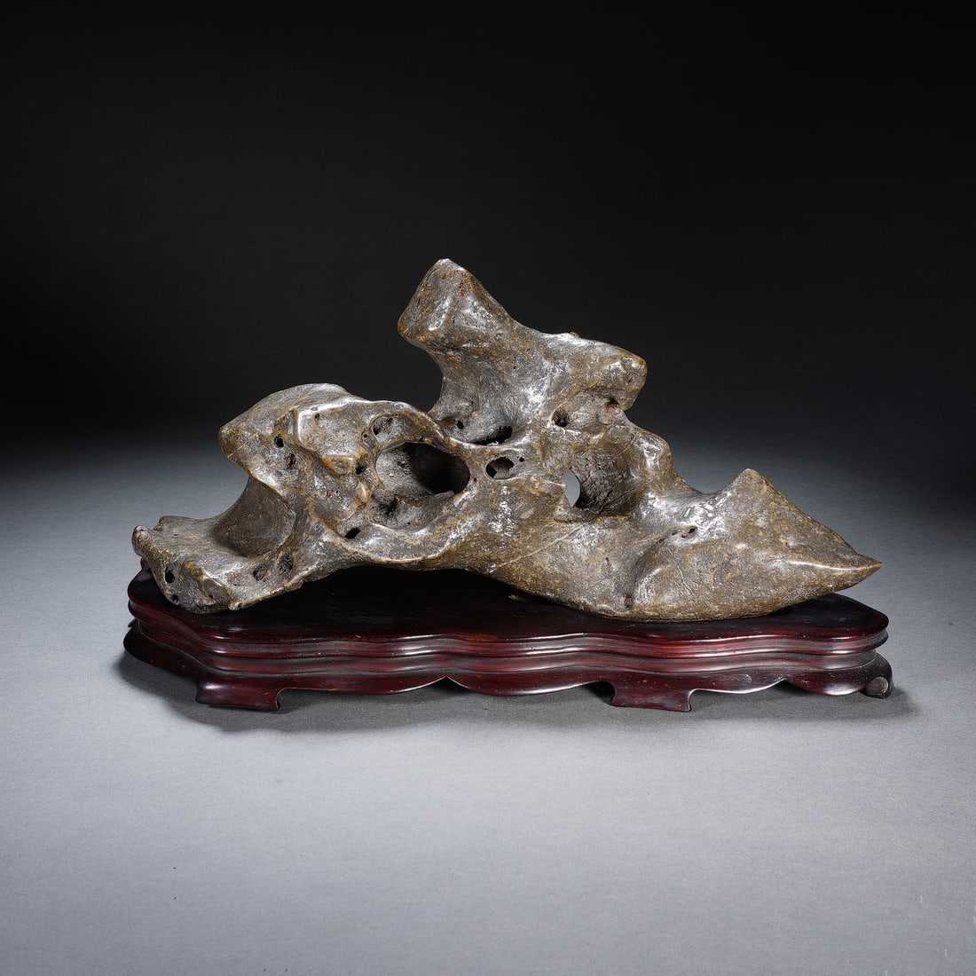 A CHINESE TAIHU SCHOLAR'S ROCK WITH STAND: A CHINESE TAIHU SCHOLAR'S ROCK WITH STAND This naturally formed Taihu viewing stone boasts an extraordinary organic structure pierced by numerous irregular hollows and undulating jagged ridges, presen
