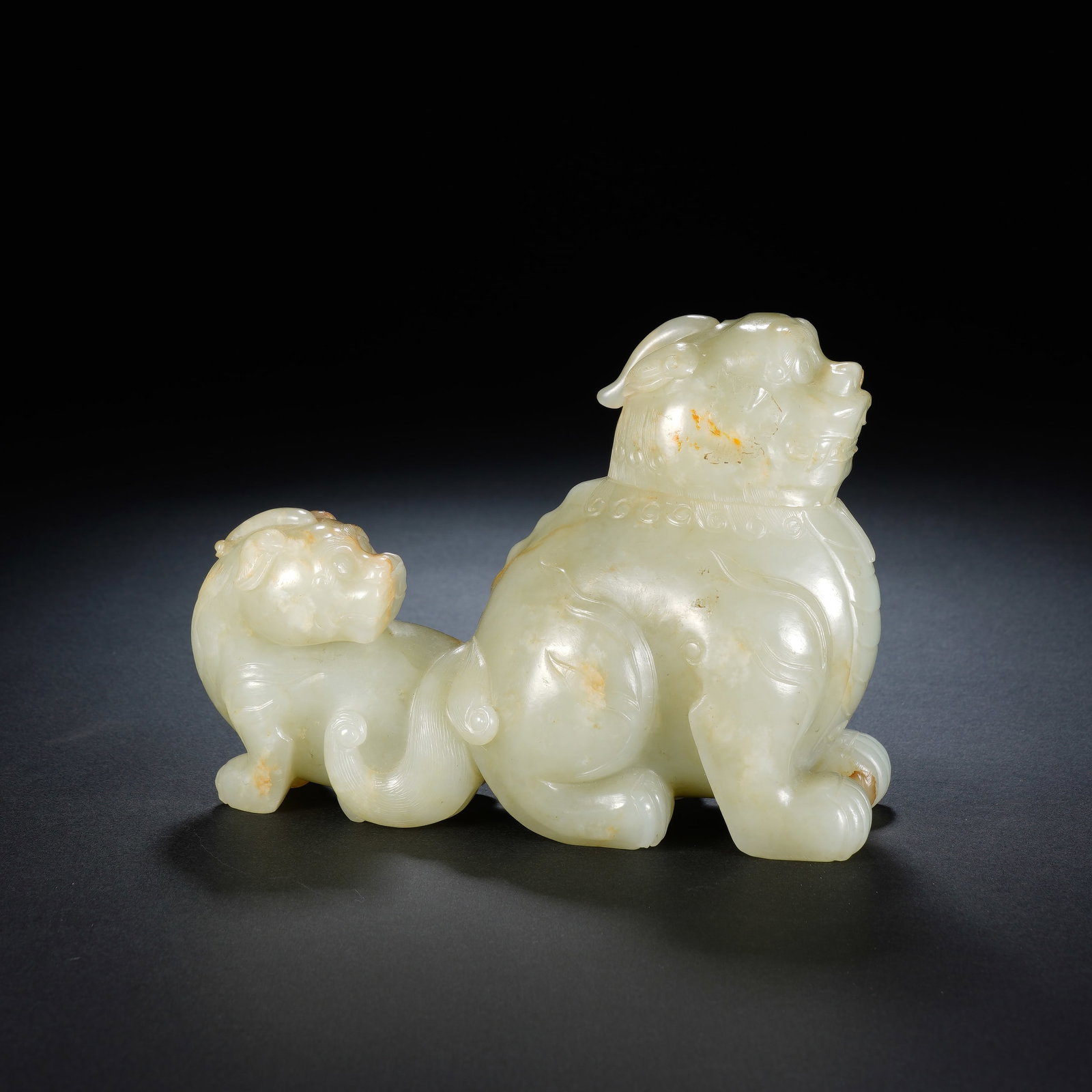 A CHINESE WHITE JADE MOTHER AND CUB AUSPICIOUS BEAST ORNAMENT: A CHINESE WHITE JADE MOTHER AND CUB AUSPICIOUS BEAST ORNAMENT This nephrite jade carving measures 13cm ? 5.5cm ? 10cm and weighs 635 grams, depicting a recumbent mythical guardian lion paired with its
