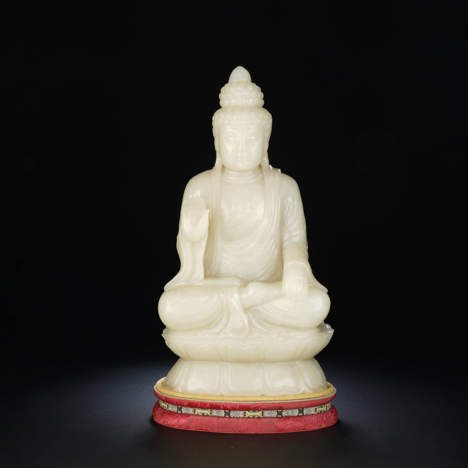 A CHINESE WHITE JADE SEATED SAKYAMUNI BUDDHA: A CHINESE WHITE JADE SEATED SAKYAMUNI BUDDHA Finely carved from smooth natural white nephrite jade, this serene Sakyamuni figure sits in full lotus position atop an integrated lotus base, with charact