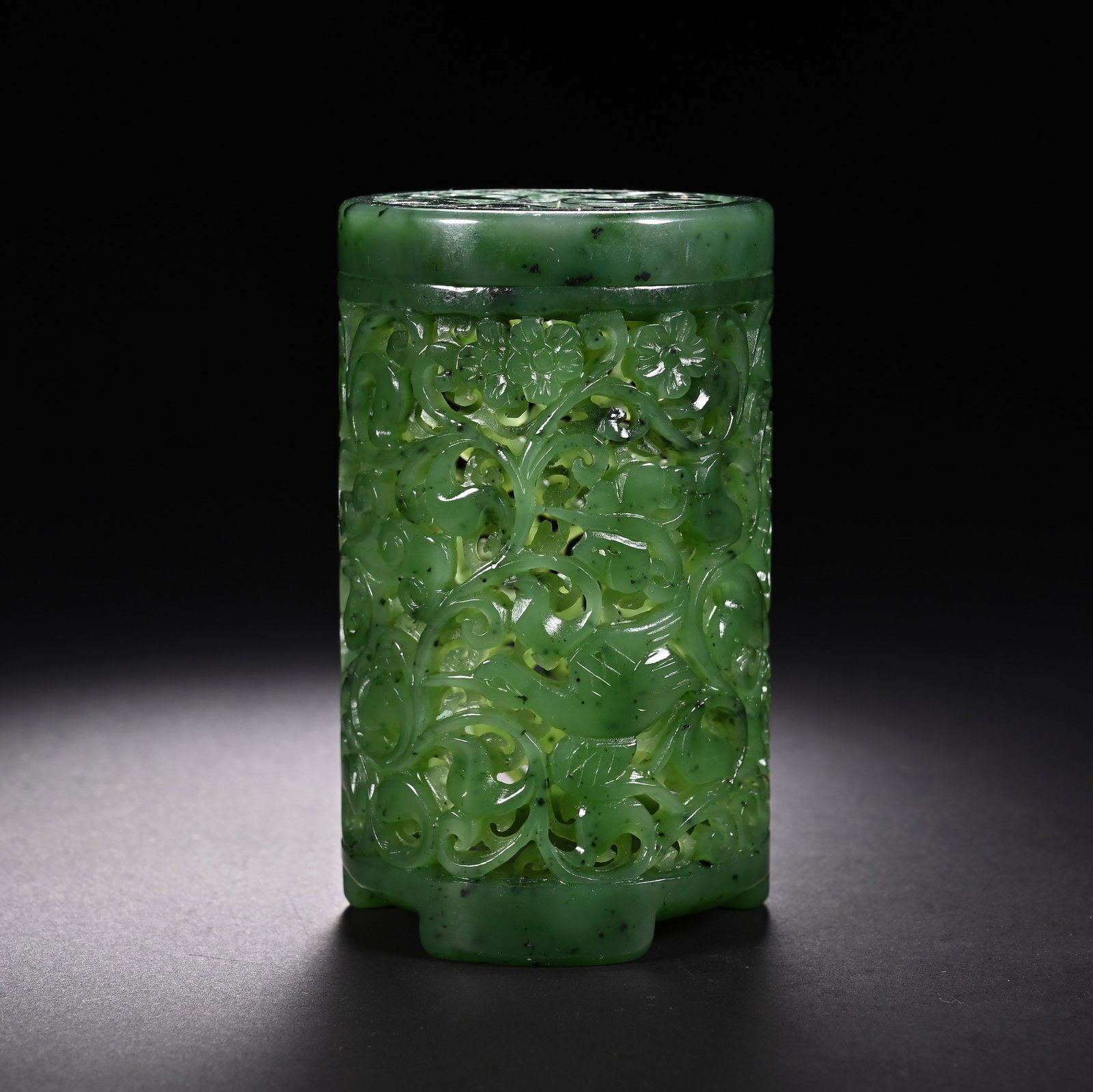 A CHINESE SPINACH JADE OPENWORK CYLINDRICAL INCENSE BURNER: A CHINESE SPINACH JADE OPENWORK CYLINDRICAL INCENSE BURNER This cylindrical censer is carved from rich spinach green nephrite jade naturally speckled with fine dark mineral flecks. The entire exterior