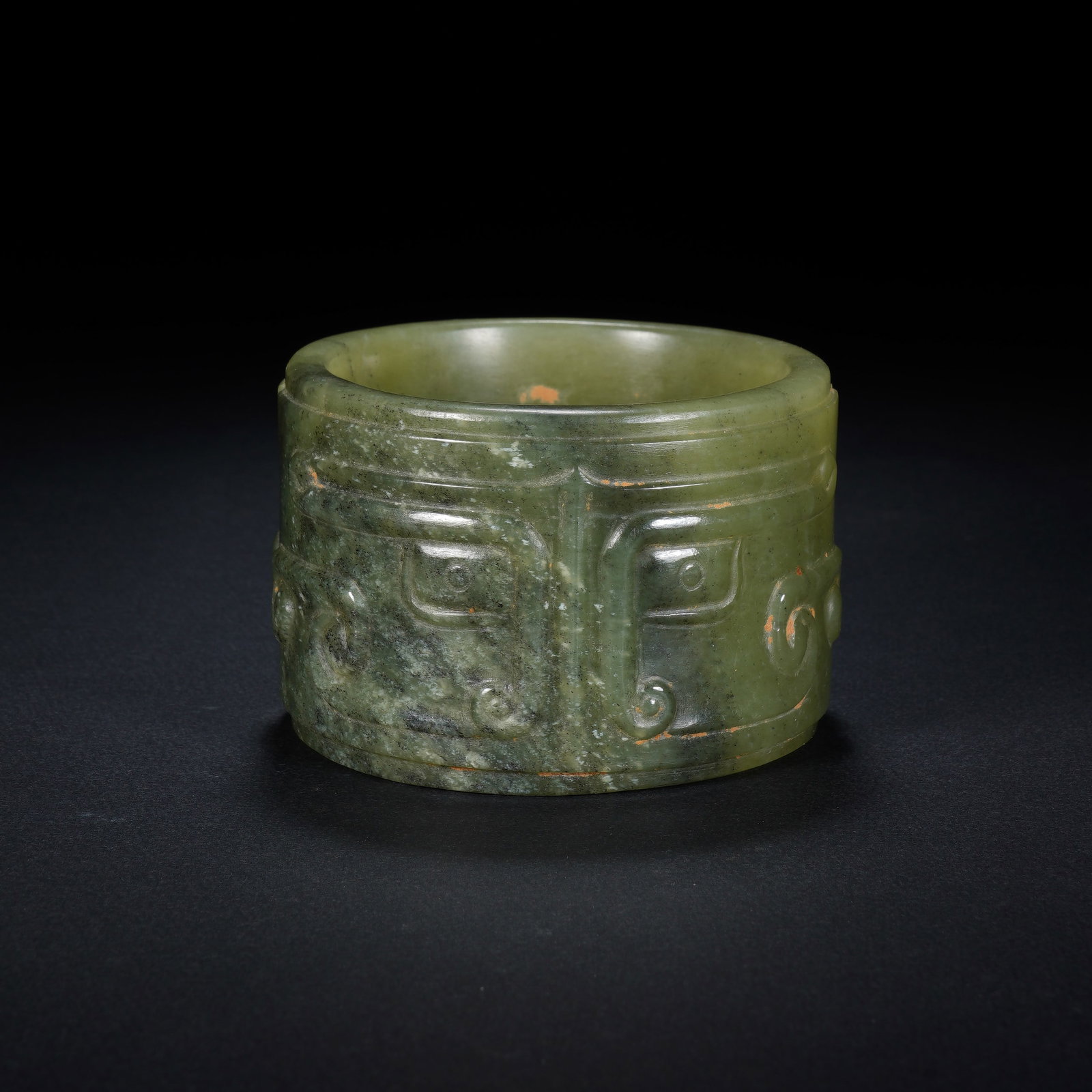 A CHINESE ARCHAIC CYLINDRICAL JADE CONG: A CHINESE ARCHAIC CYLINDRICAL JADE CONG This short cylindrical jade cong measures 7.7cm across and 5.2cm tall, weighing 237 grams. Its exterior is partitioned into vertical panels each bearing low-rel