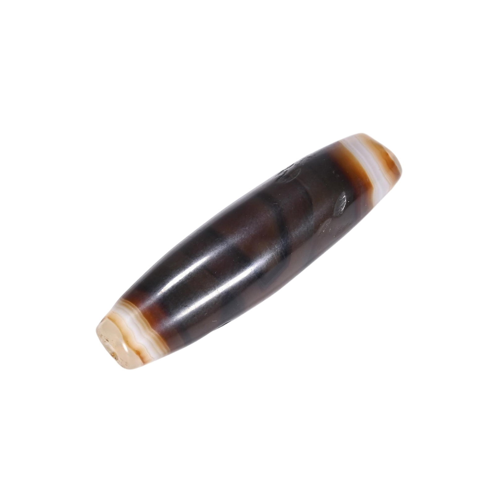 A CHINESE BANDED AGATE DZI BEAD: A CHINESE BANDED AGATE DZI BEAD Elongated and tapering at both ends, this dzi bead is crafted from natural banded agate with smooth polished surfaces showcasing fluid layered bands of deep espresso br
