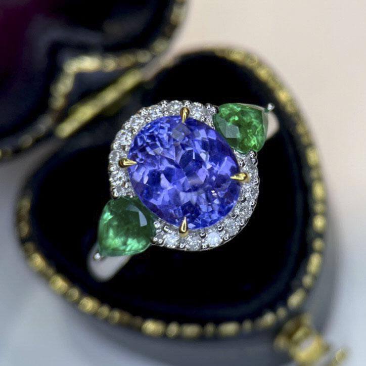 14K White Gold 4.85 CTW Tanzanite & Emerald Ring: Ref:2022710066 Gold Content:14K White Gold For people:Women Ring Size:7.25US Main Stone:Tanzanite Number of stones:1 Shape:Oval Carat Total Wt:3.65ct Color:Blue Cut Grade:G Adjacent Gemst