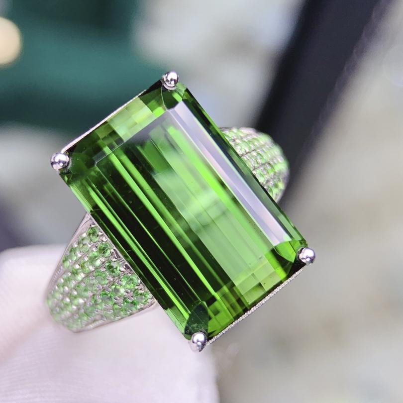 14K White Gold 9.62 CT Tourmaline & Tsavorite Ring: Ref:1109018 Gold Content:14K White Gold Total Item Weight:6.9grams Ring Size:7.25US Main Stone:Tourmaline Number of stones:1 Shape:Emerald Carat Total Wt:9.62ct Color:Green Cut Grade:G Adjacen