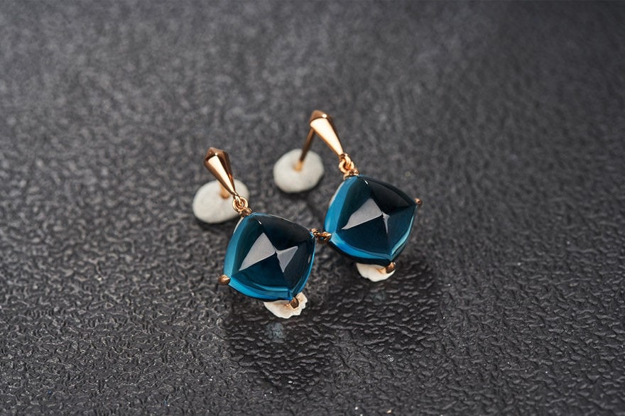 14k Gold 15 Ct Natural Topaz Earrings: Ref:231111087 // gold content:14k gold // main gemstone:topaz // shape:sugar-loaf // carat weight:15ct // color:blue // treatment:natural // Condition: New Low Estimate: 2400.00 High Estimate: 3600.0