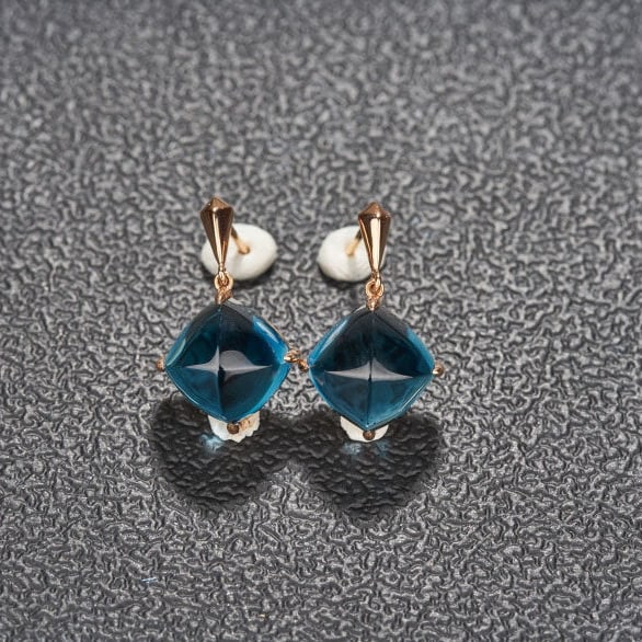 14k Gold 15 Ct Natural Topaz Earrings: Ref:231126059 // gold content:14k gold // main gemstone:topaz // shape:sugar-loaf // carat weight:15ct // color:blue // treatment:natural // Low Estimate: 2300 Condition: New High Estimate: 3400