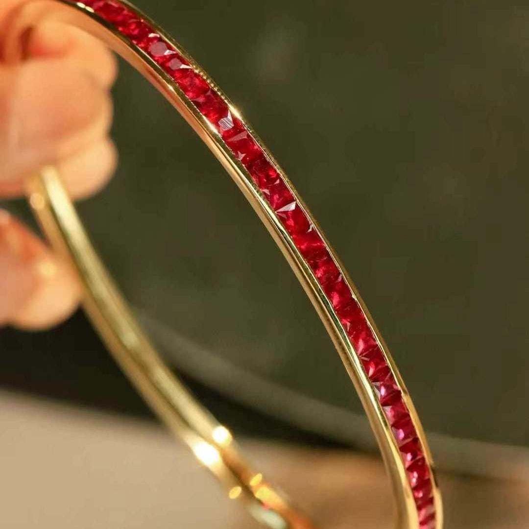 14k Gold 2.87 Ct Natural Ruby Bangle: Ref:231000195 // gold content:14k gold // main gemstone:ruby // shape:princess // carat weight:2. 87ct // color:red // treatment:natural // Condition: New Low Estimate: 7700.00 High Estimate: 12000.00