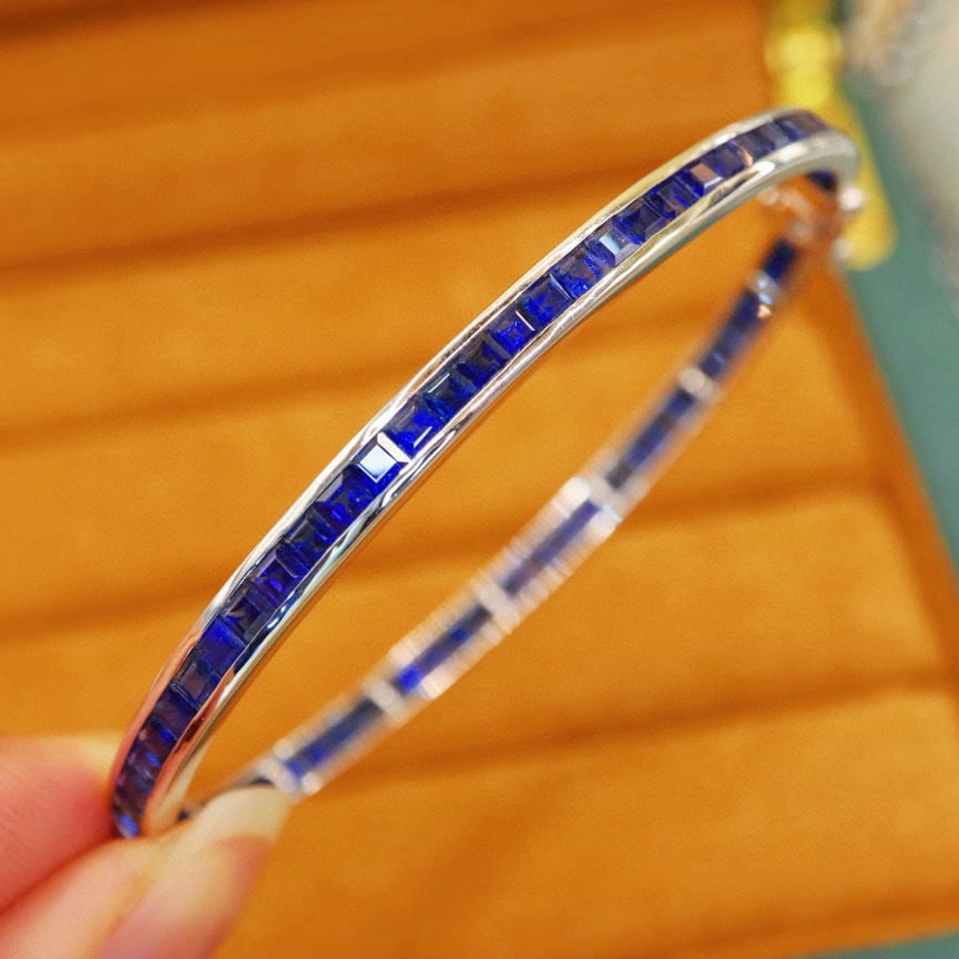 14k Gold 9.16 Ct Natural Sapphire Bangle: Ref:231008244 // gold content:14k gold // main gemstone:sapphire // shape:square // carat weight:9. 16ct // color:royal blue // treatment:natural // Low Estimate: 10000 Condition: New High Estimate: 1