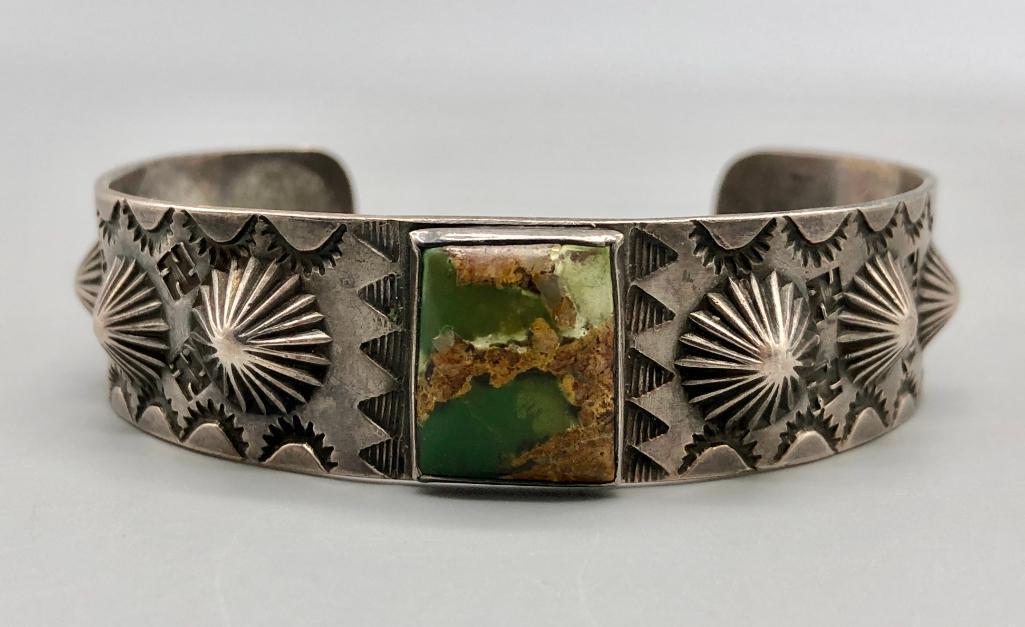 Vintage Turquoise Sterling Silver & Whirling Log Stamped Bracelet: Available in this lot is a vintage turquoise and sterling silver bracelet. This remarkable bracelet features a square-cut turquoise cabochon in a wonderful green color, surrounded by fine repousse wor