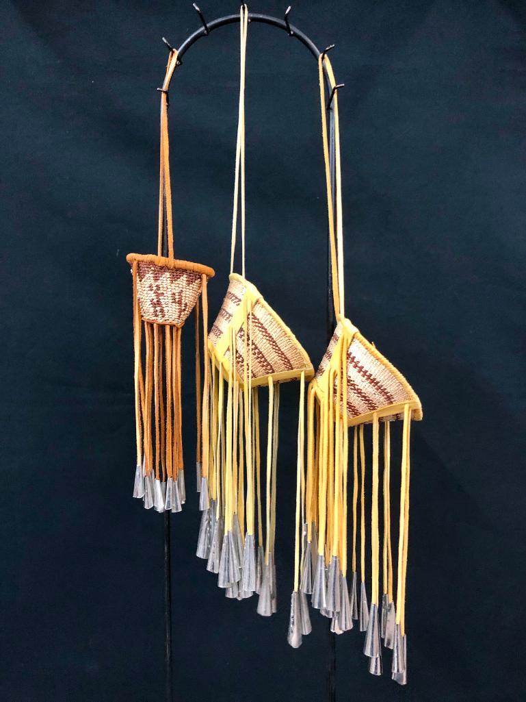 Three Mini Apache Burden Baskets: Offered in this lot are three mini Apache burden baskets. Apache Burden baskets were originally made as utilitarian baskets for gathering berries and they were decorated with tin cones to make noise t