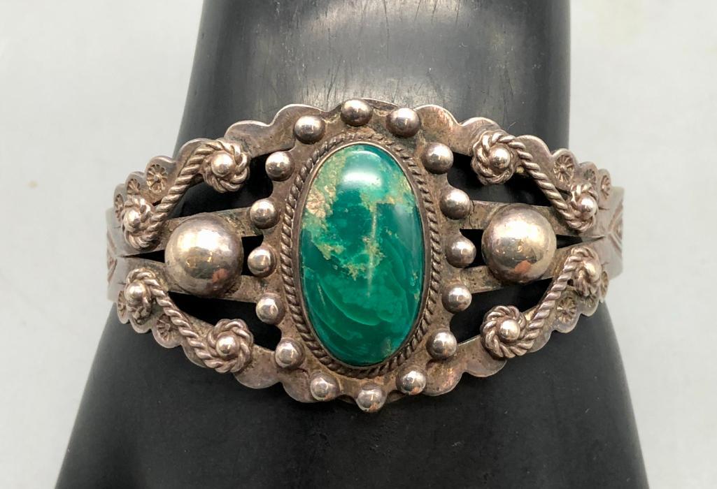 Fred Harvey Era Turquoise Bracelet: Featured here in this lot is a Fred Harvey era turquoise bracelet. This remarkable piece features a green turquoise cabochon in the center, with silver half circles dotting the nice cutout band, with 