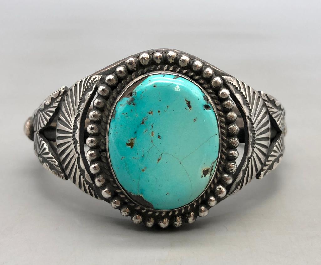 Turquoise and Sterling Silver Bracelet: Featured here is a turquoise and sterling silver bracelet. This incredible piece features a beautiful blue turquoise cabochon in the center of the piece, with nice hand stamped silver pieces, twisted 