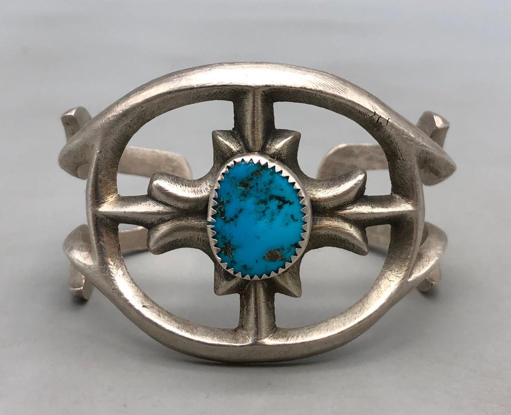 Vintage Turquoise and Sandcast Bracelet: In this lot is a vintage turquoise and sandcast bracelet. This sterling silver and turquoise bracelet beautifully features a turquoise cabochon set in a sawtooth bezel surrounded by an ornate sandcast
