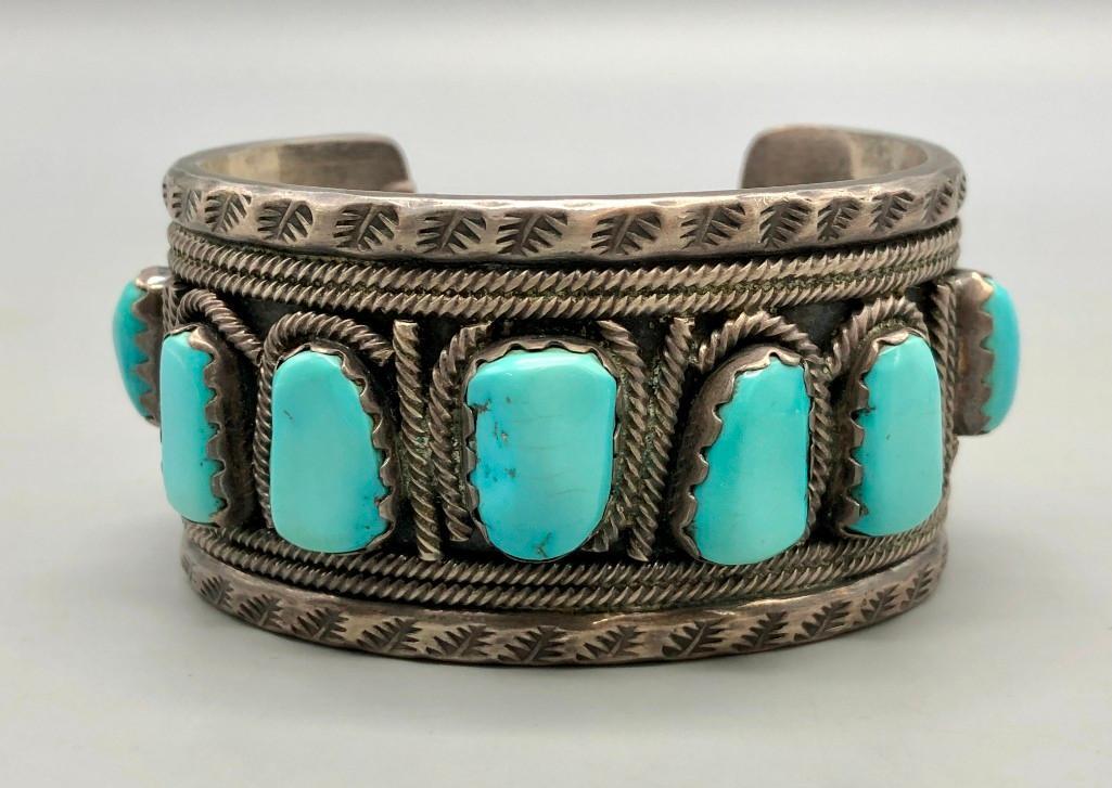 Hefty Nine Stone Turquoise Bracelet: Available here is a hefty nine stone turquoise bracelet. This stunning bracelet features nine incredible turquoise cabochons in handmade sawtooth bezels with twisted wire accents all throughout the cu